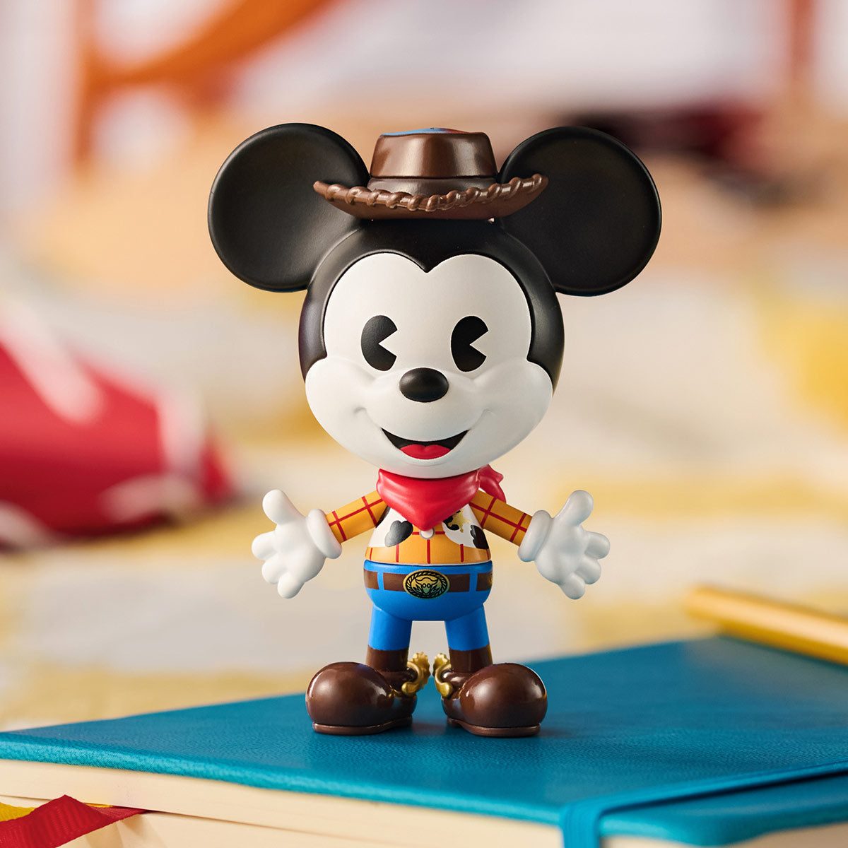Disney Mickey Remixed: Mickey Meets Pixar Series Figures - Preorder. Mickey Mouse cowboy figurine on a notebook, part of a collectible blind box series.