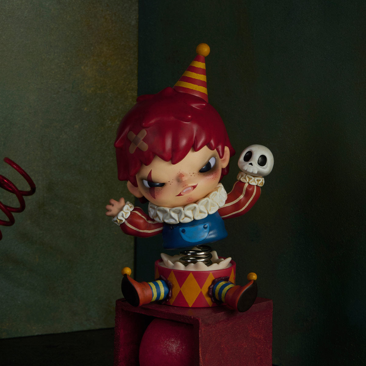 Hirono Monsters' Carnival Series: Mischievous clown jack-in-the-box with red hair, impish grin, striped hat, and macabre skull. Preorder for November 2025.