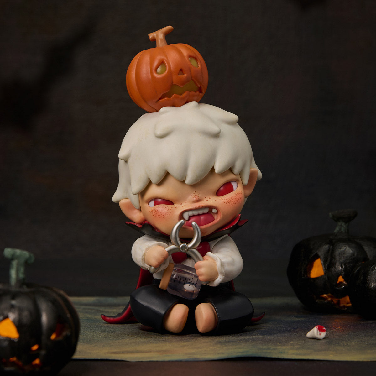 Hirono Monsters' Carnival Series Figure: Chibi vampire boy with pumpkin hat, holding pliers. Preorder for November 2025. Includes collectible tooth jar and spooky jack-o-lanterns.