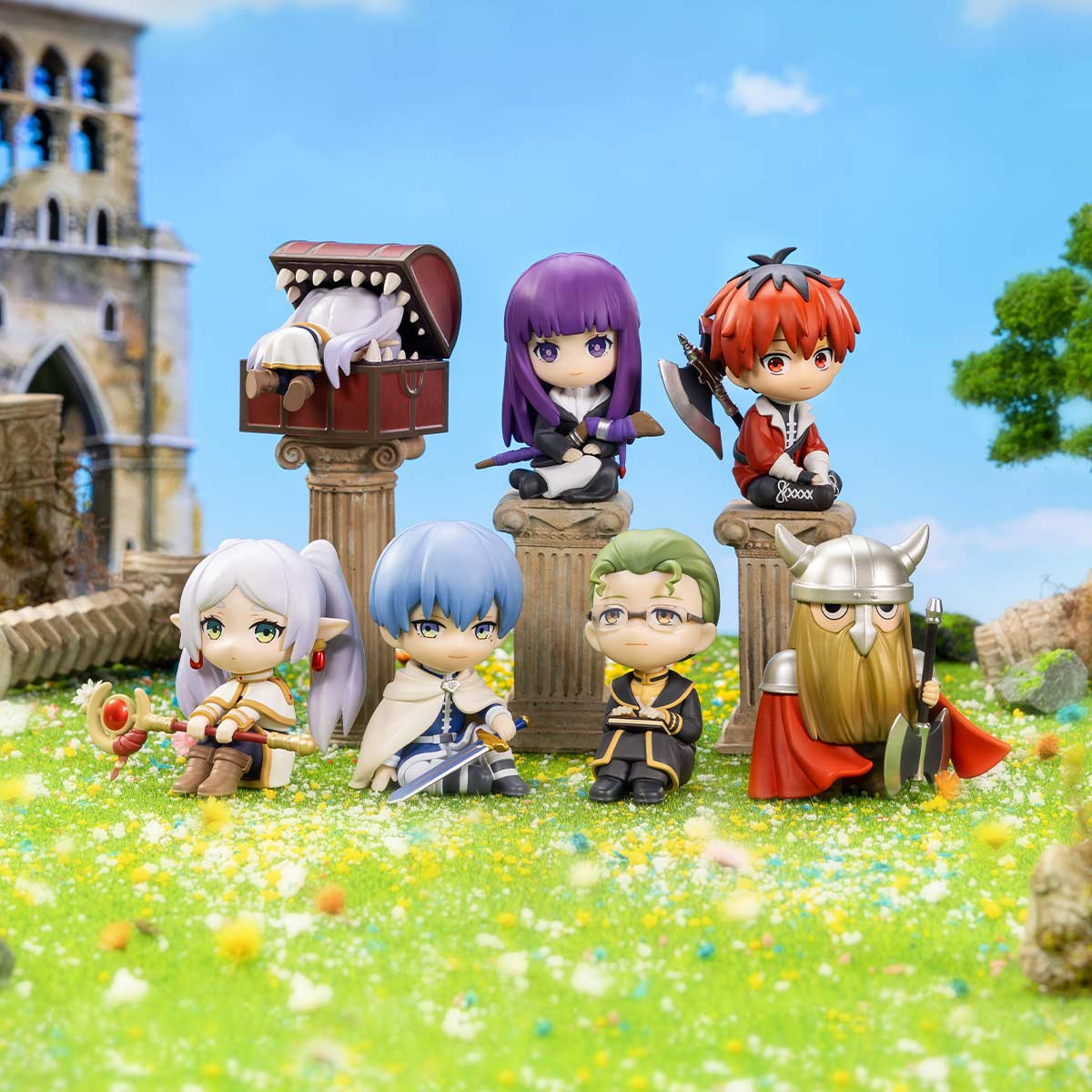 Frieren: Beyond Journey's End Series Figures, featuring chibi-style fantasy adventurers and a mimic chest, set on columns in a meadow with a ruined tower backdrop.