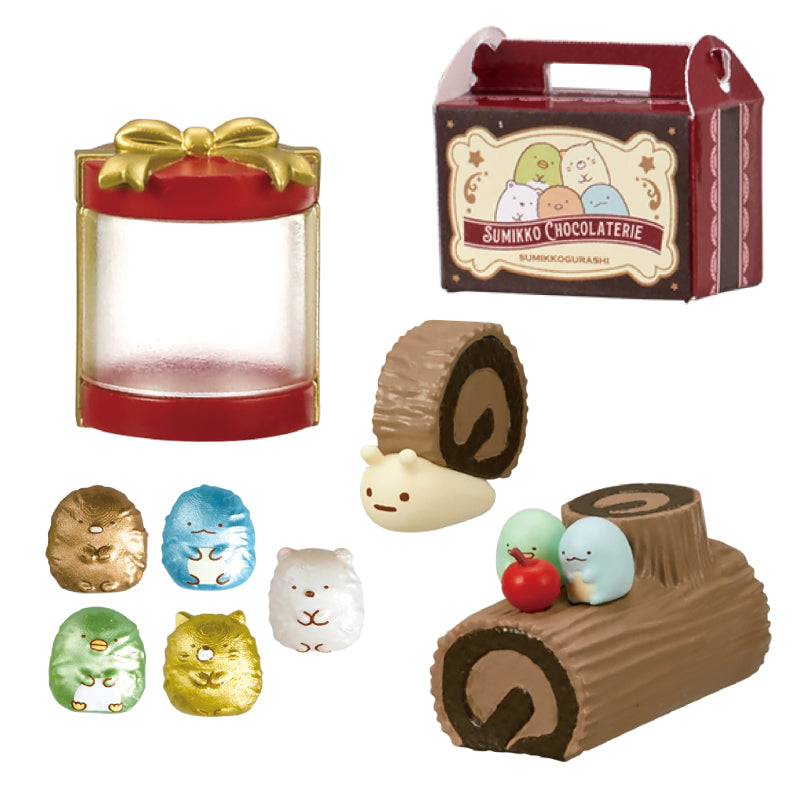 SUMIKKO CHOCOLATERIE Re-ment Blind Box Series mini play-set with a carry-along box, display jar, chocolate log slices, Sumikko figures, and foil-wrapped chocolates.