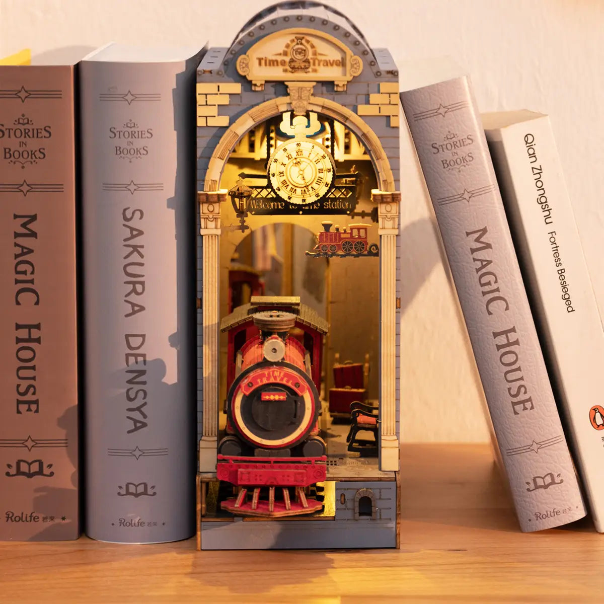 A DIY miniature house book nook featuring a clock with a train, a toy train in a tower, and a book on a shelf. Product title: Book Nook Kits For Adults - Time Travel.