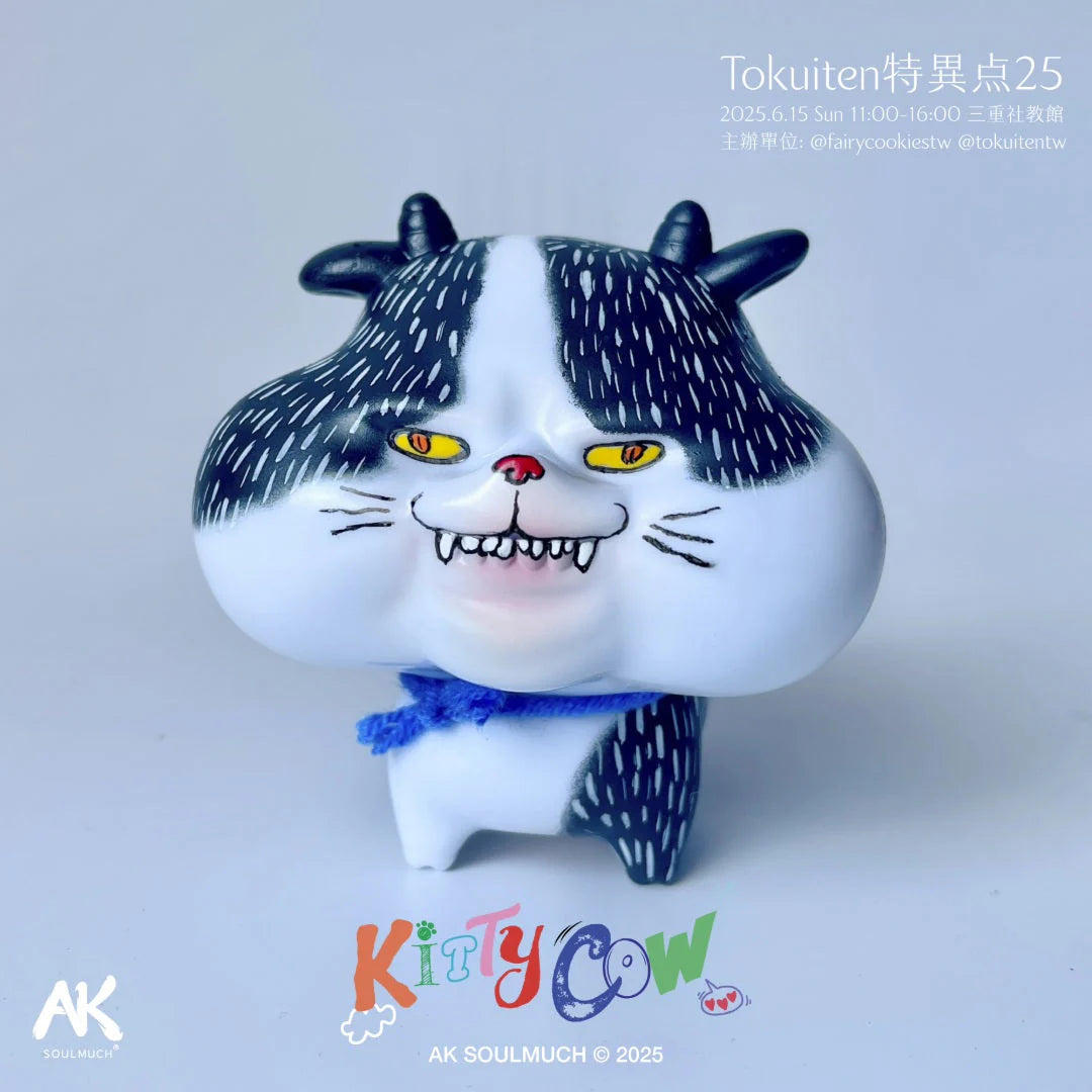 KittyCow by AK Soulmuch: A whimsical designer toy blending cat features with cow patterns, complete with fangs and a blue scarf, showcased for Tokuiten 2025.