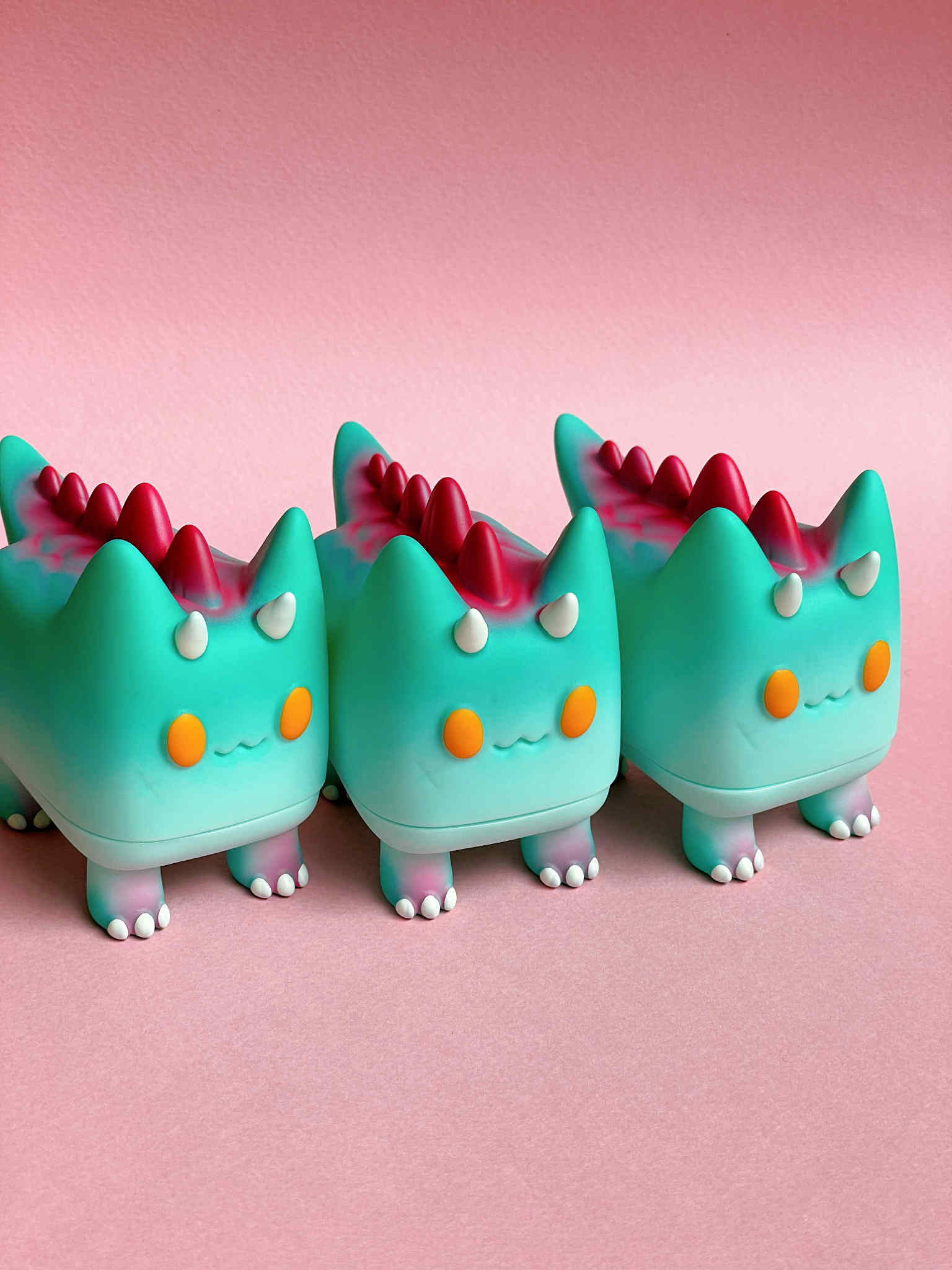 DiDi (Dino cat) by Rato Kim - Preorder: Three mint-green, cat-dragon vinyl figures with horns, orange cheeks, and red back spikes. 6.5x7.5x5.7cm sofubi art toys.