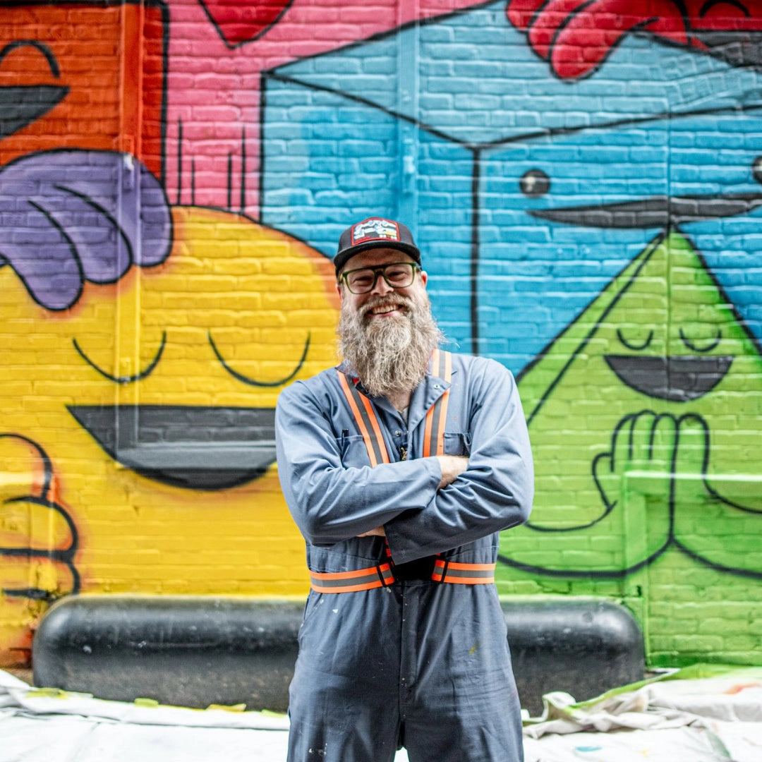 Bearded man in blue coverall, smiling before a vibrant mural, promoting Pickagram 3D Puzzle X Artist_01 Shawn Smith, reflecting Chicago's artistic spirit.