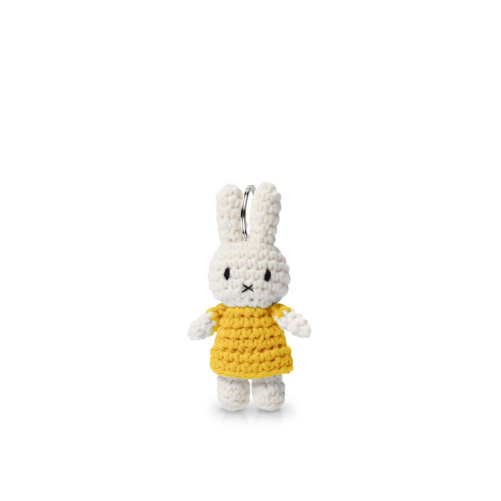 A knitted bunny doll in a yellow dress, resembling Miffy, close-up view. Product: Miffy Crochet Keychain, 1.3x1x2.4 in, CE Certified plastic toy for ages 3+. From Strangecat Toys.