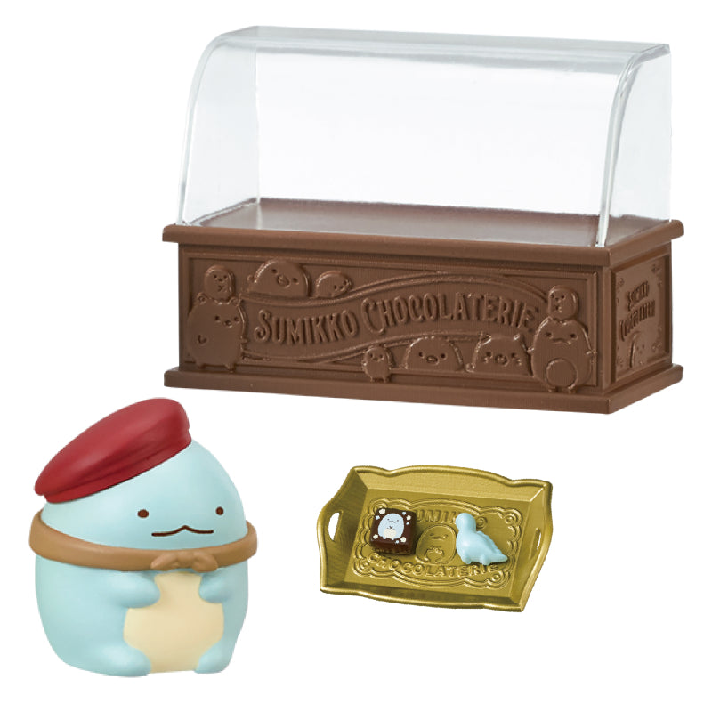SUMIKKO CHOCOLATERIE Re-ment Blind Box Series: Features a diorama with a turquoise figurine in a red beret, a chocolate square, and a bird figure in a display case.