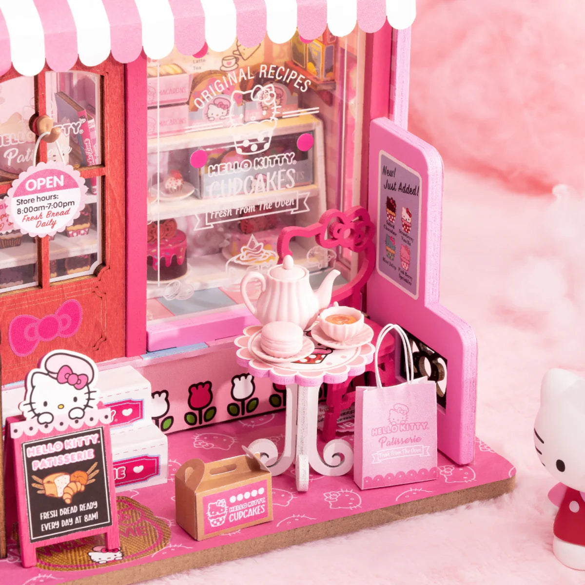 Hello Kitty Patisserie diorama with bistro table, teapot, macaron, and cupcakes. Includes Hello Kitty figure and LED light. Ideal for collectors and art toy enthusiasts.