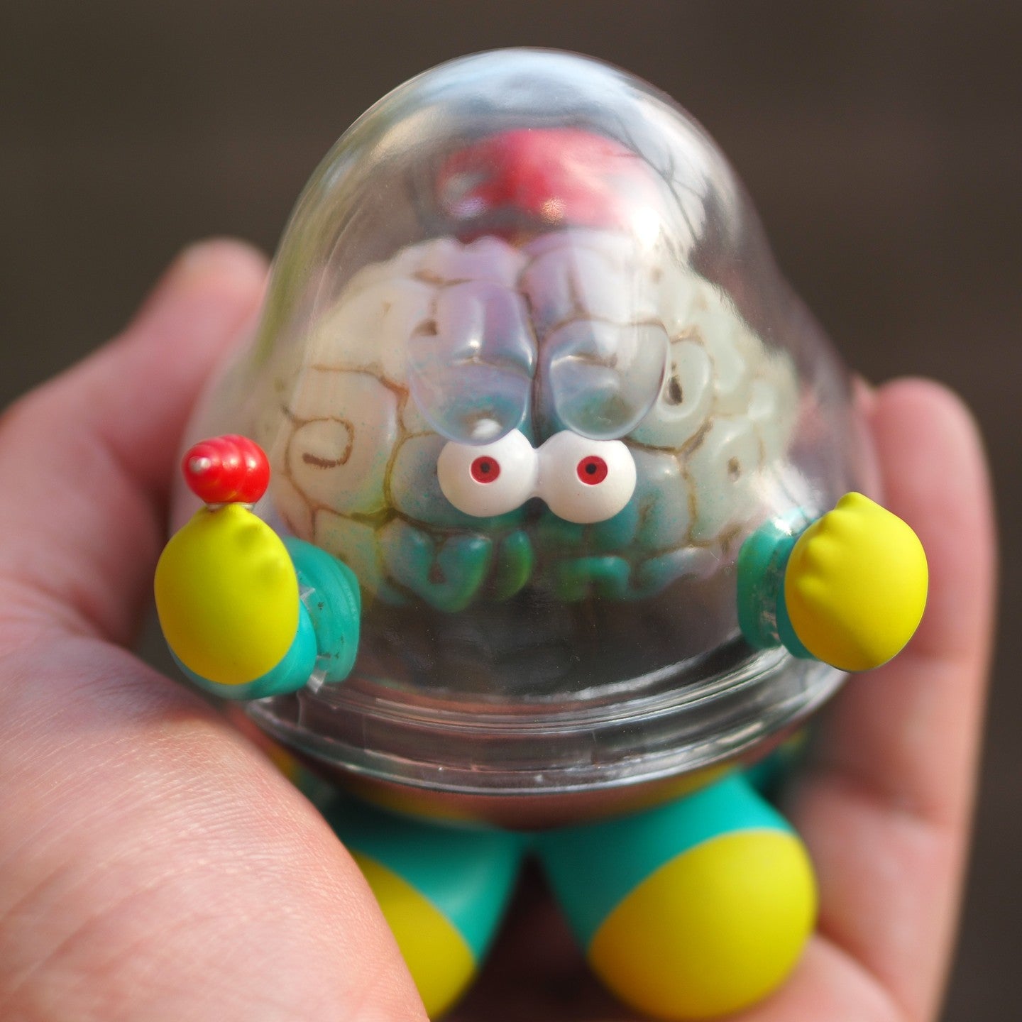 A hand holds Mr.Brain - Brains Attacks toy, a 9 cm tall sofubi/resin figure. Preorder - Ships Late May 2024. From Strangecat Toys.