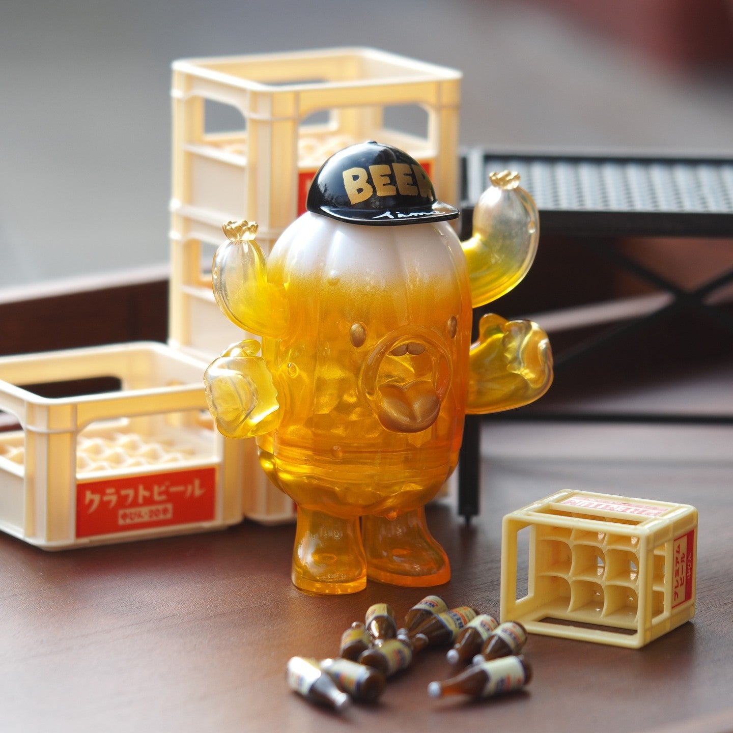 A blind box toy named BEER PATU, made of soft vinyl, 10 cm tall, depicted on a table with a plastic toy bear and small bottles. Preorder - Ships Late May 2024.