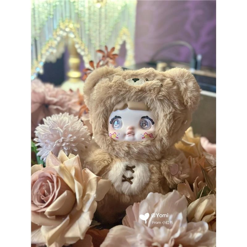 Nommi - Loveliness Never Ends Plush Blind Box Series: A stuffed doll in a bear outfit surrounded by flowers, part of a collectible blind box series.