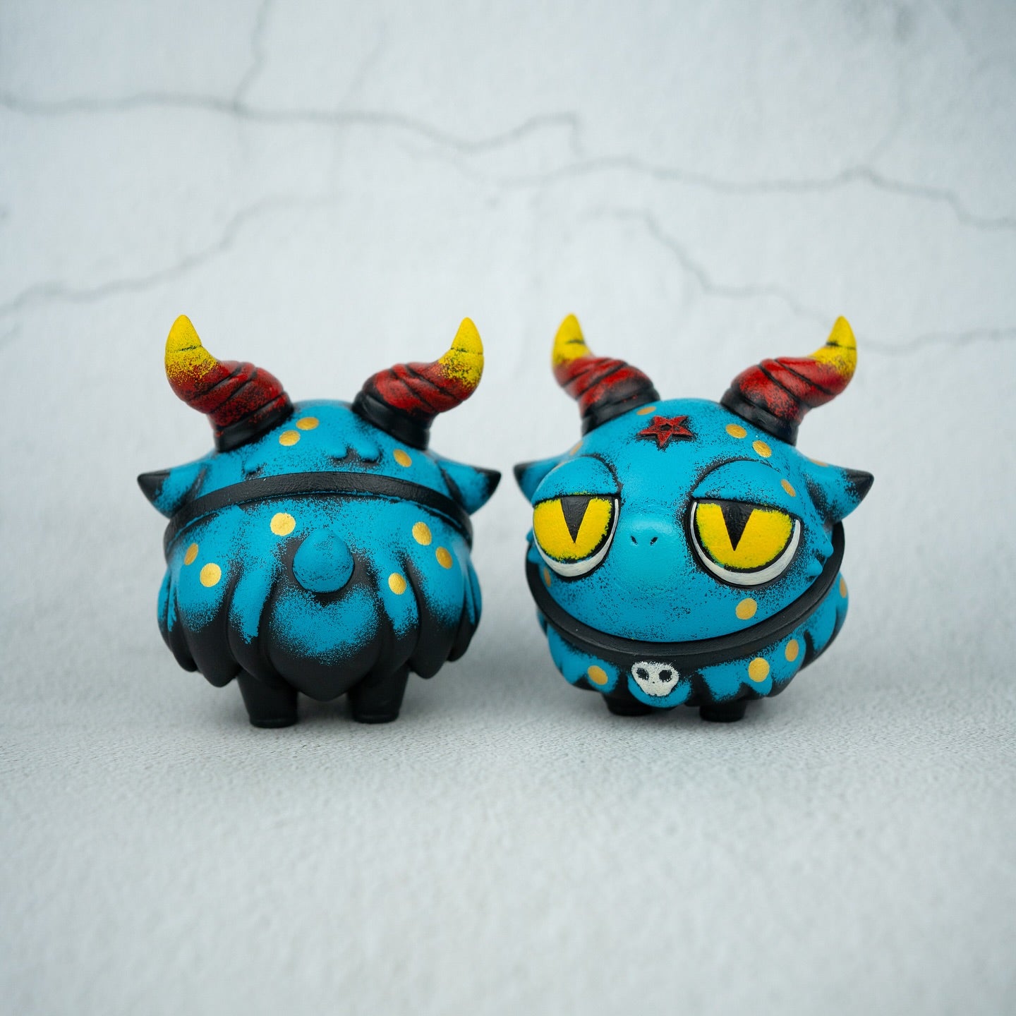 Snake Bobbi by Zintears: Two 10cm turquoise vinyl figures with horns, yellow polka dots, and a skull motif, showcasing front and back views. Limited edition collectible.