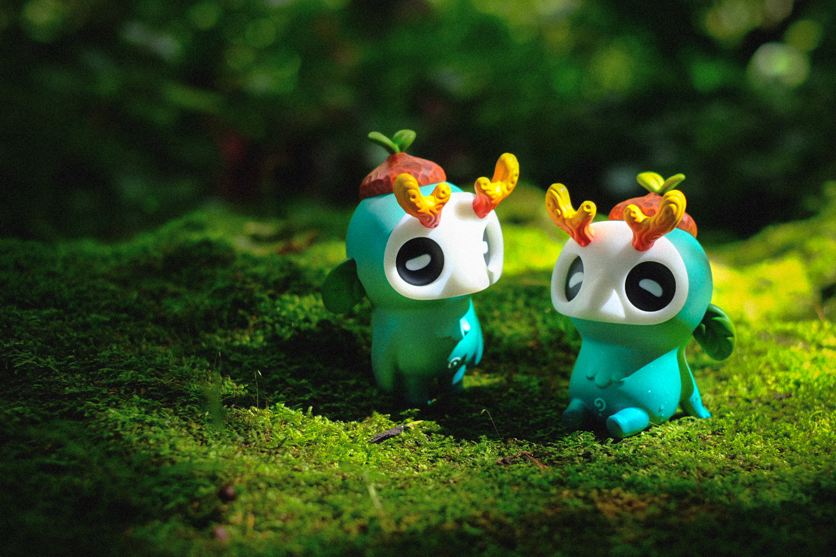 Ori Muffinn: The forest spirit figurines with acorn hats, antlers, and glowing elements, set on moss, highlighting nature-inspired, collectible art toys by Madkids.