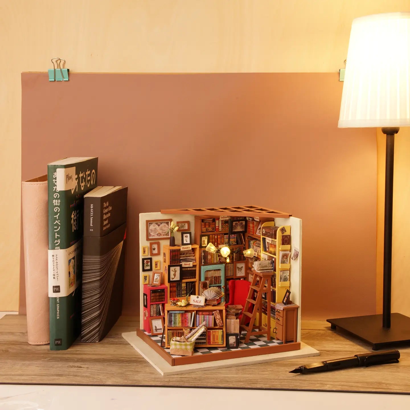 A miniature dollhouse featuring a bookcase, ladder, and lamp. Sam's Study Rolife Library Diy Miniature Dollhouse offers magical services in a cozy setting. Dimensions: 8.3 x 5.2 x 6.9 in.