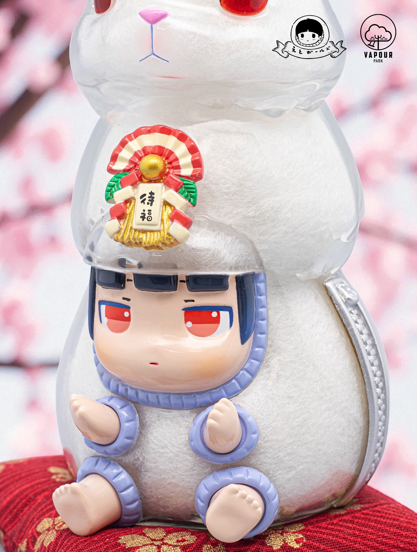Kigurumi Bunny by Ebimomo & Vapourpark: A clear vinyl cat figure with a chibi doll inside, on a red cushion, logos indicate limited-edition preorder collectible.