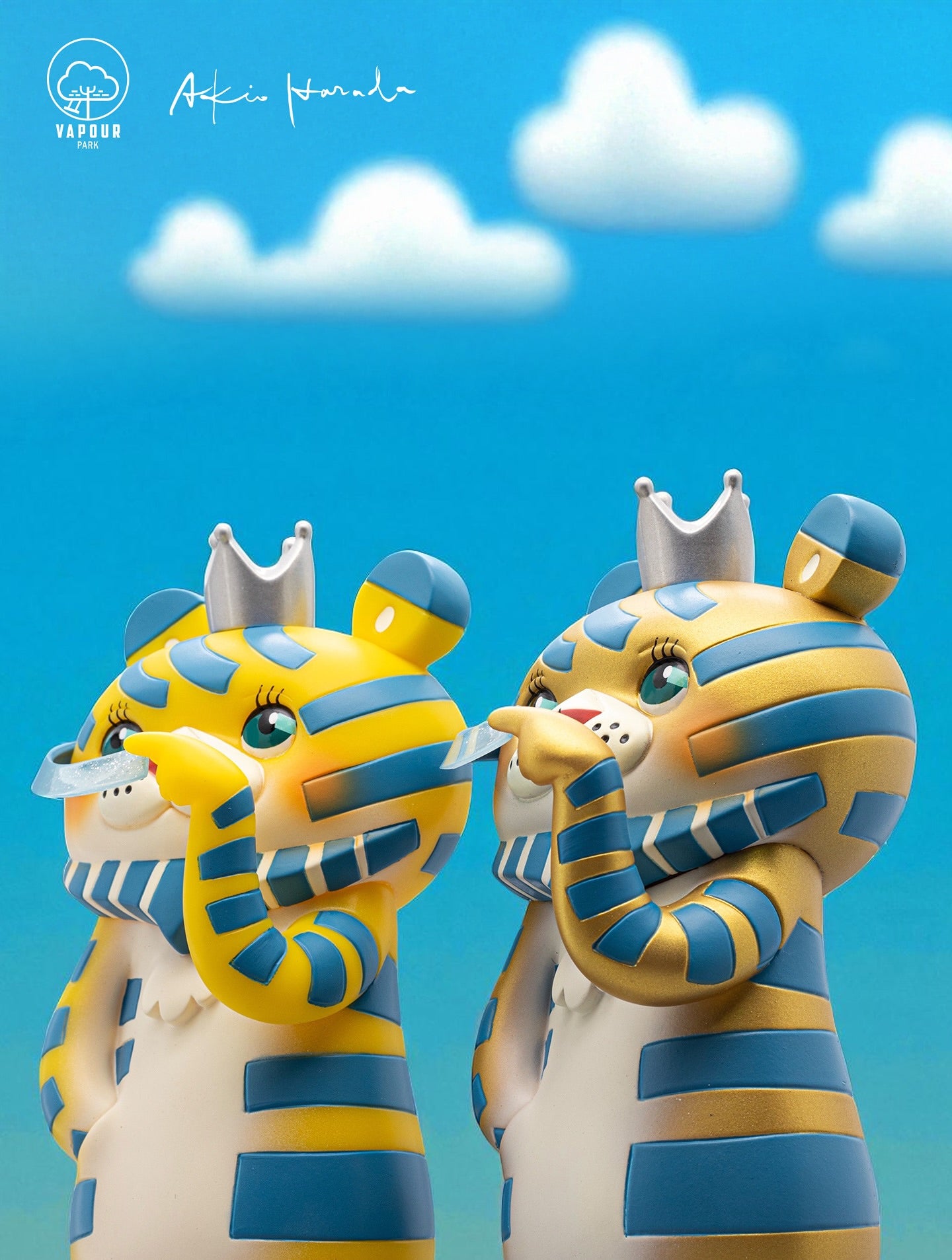 Bearded Tiger 6th Colorway by Akio Harada & Vapourpark: two collectible vinyl figures with tiger-elephant features, silver crowns, and translucent ribbons, set against a sky backdrop.