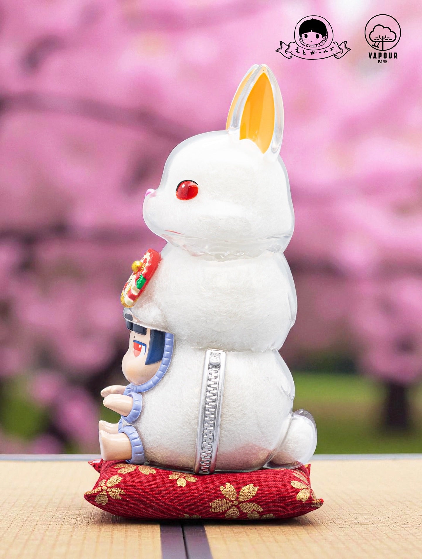 Kigurumi Bunny by Ebimomo & Vapourpark - Preorder: A 15cm designer figurine featuring a rabbit shell with a chibi person inside, posed on a red cushion.