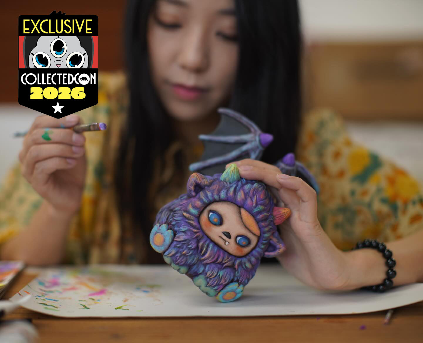 Artist hand-paints a limited edition ZuZu Monster by Pucky, a designer toy with cartoonish features, at CollectedCon 2026, featuring exclusive edition card.