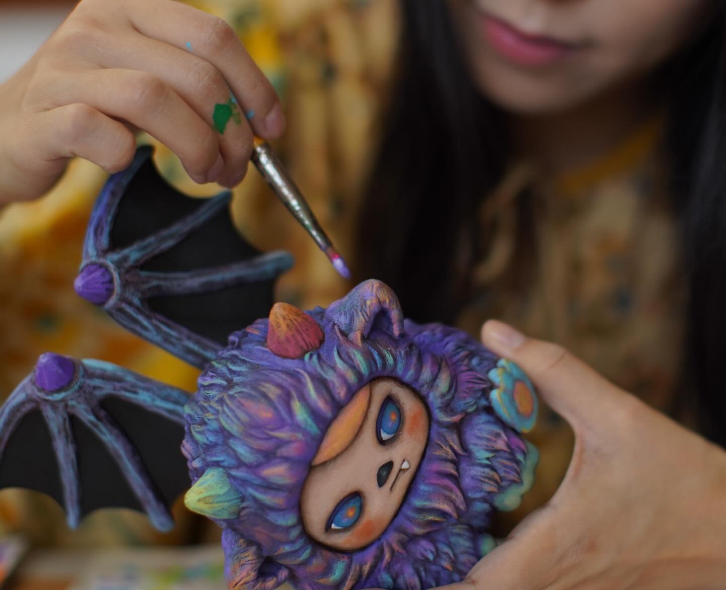 ZuZu Monster by Pucky being hand-painted, featuring bat wings and big eyes, limited edition figurine, showcasing vibrant artistry and craft.