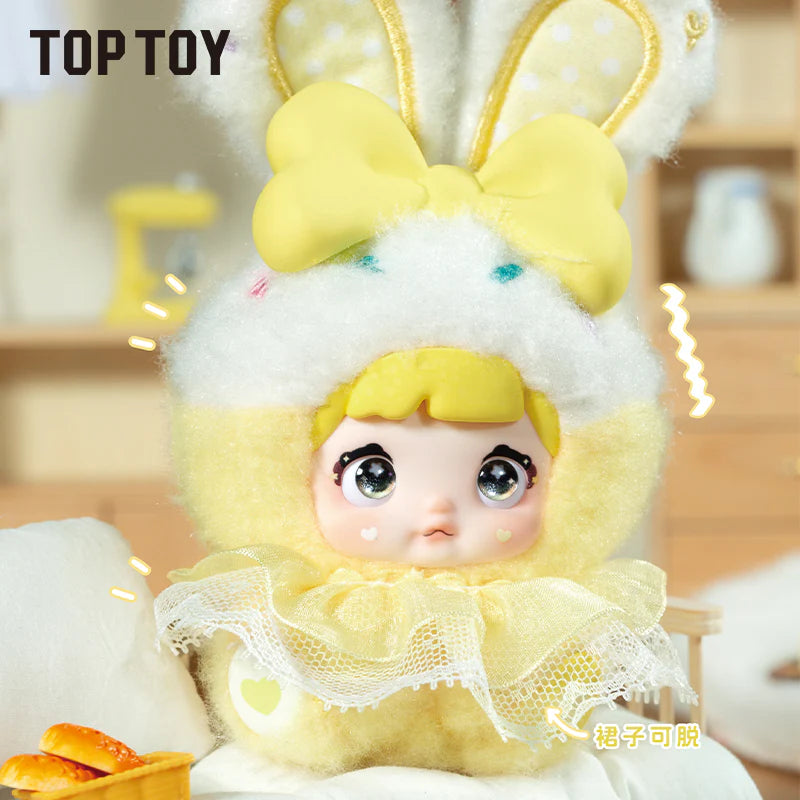 Nommi Baby Sweetheart Bunny Plush Blind Box: a plush doll in a fluffy yellow bunny outfit with sparkly eyes, lace collar, and bow-topped ears.