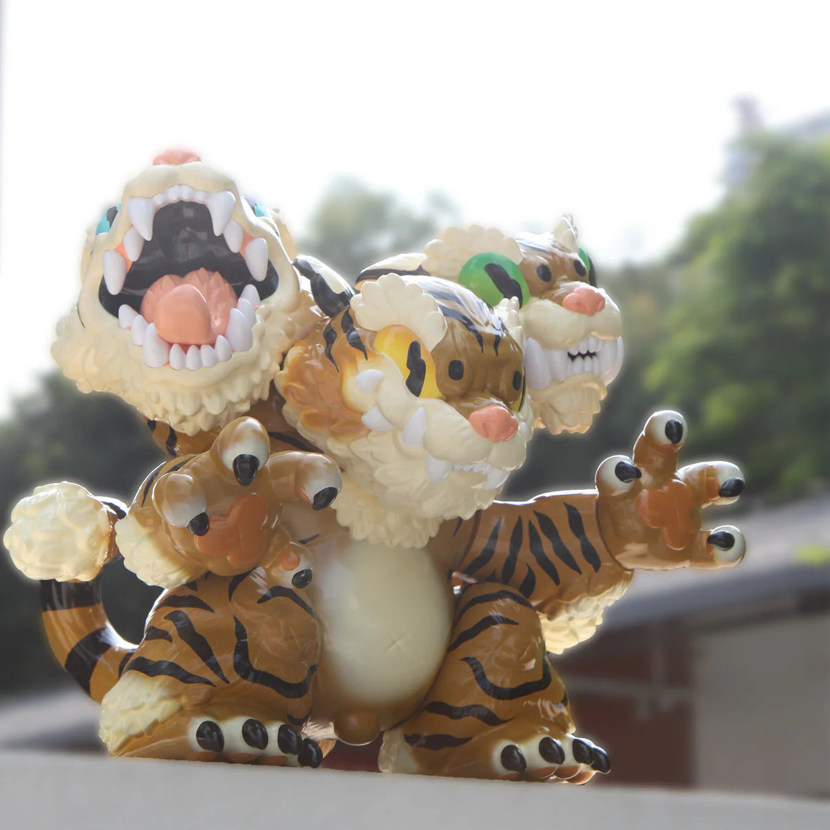 Three Headed Fierce Tiger Koshow by Grape Brain, a 35cm vinyl toy with snarling expressions, tiger stripes, and glossy finish, displayed outdoors.
