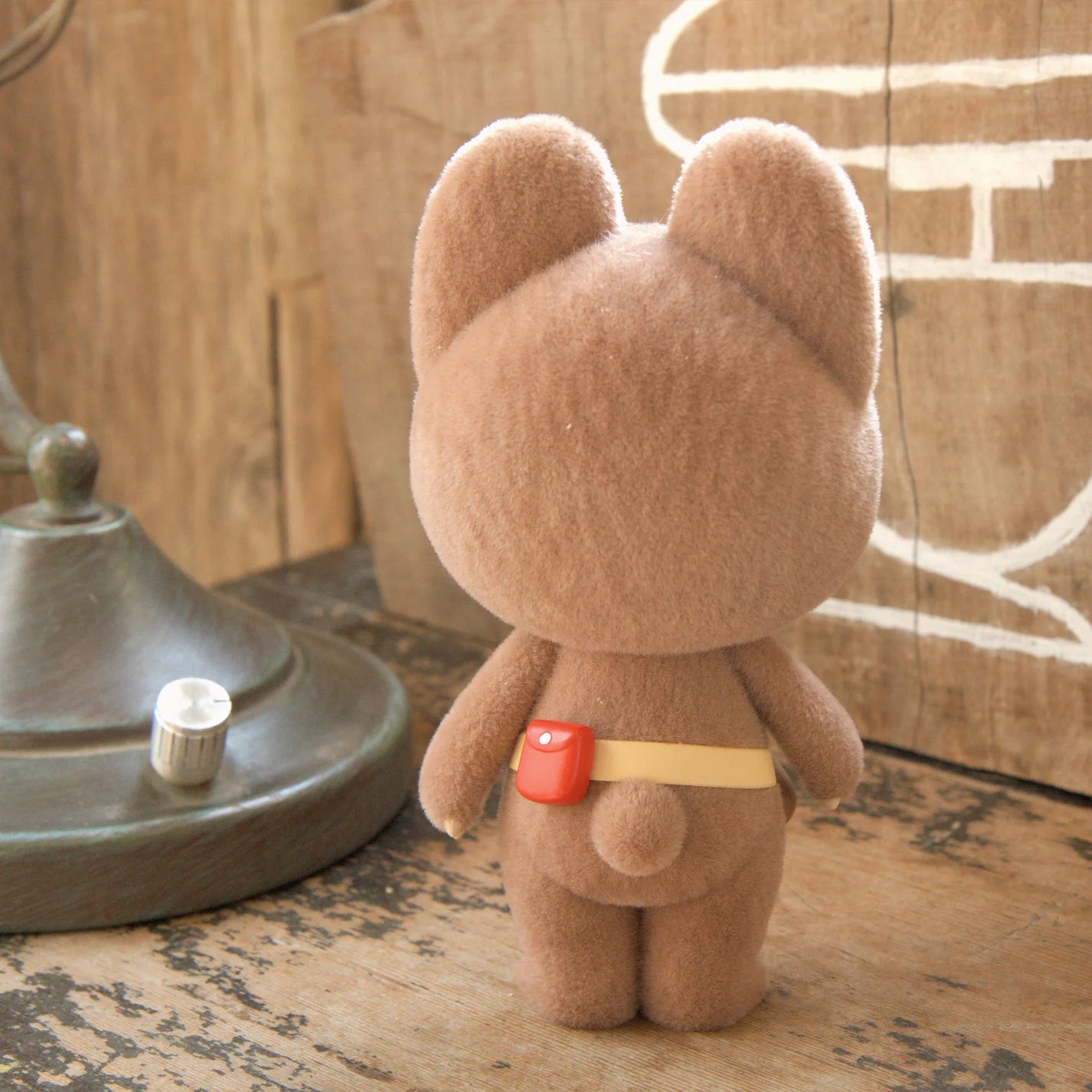 KUMARU THE FOREST BEAR FOREST FIXES vinyl figure, 16cm, with a yellow belt and red pouch, viewed from behind on a wooden surface. Preorder available.