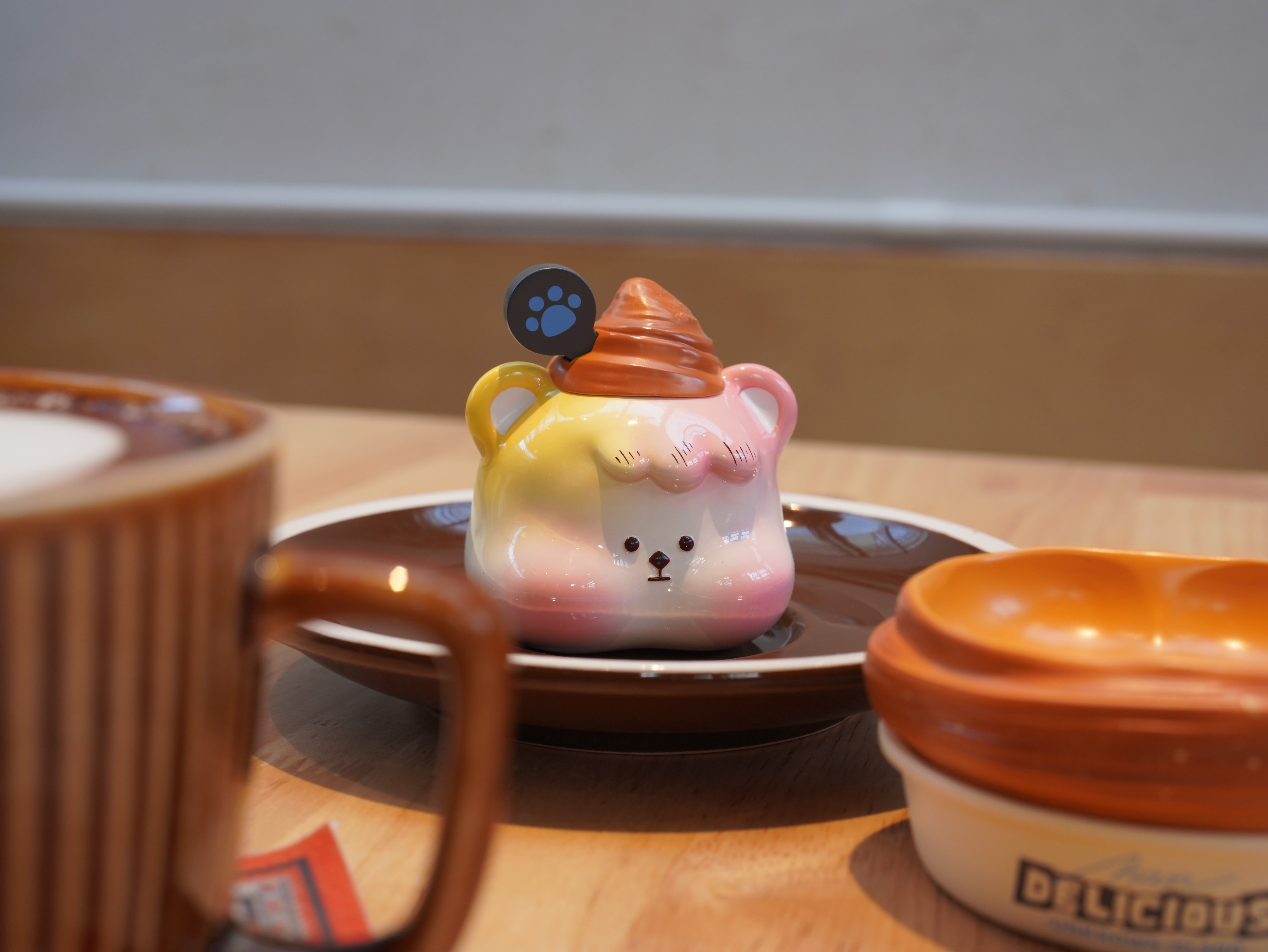 Croissant Han Han ceramic teacup on saucer, resin material, close-up of cup and plate, small bear-shaped object with hat, container detail.