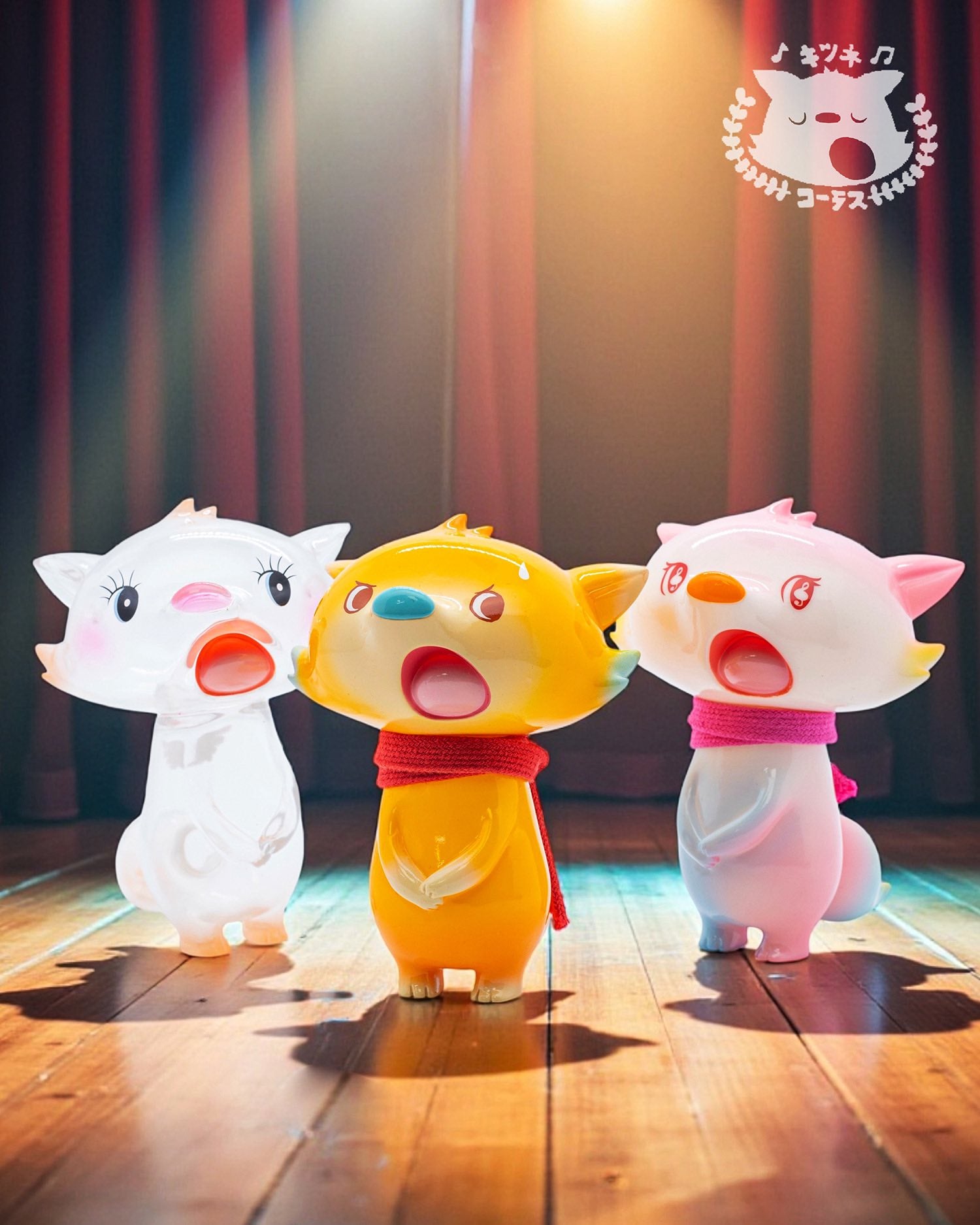 Fox Chorus Serie - Billy by Ok Luna: Three cartoon animal figurines with wide-open mouths on a stage, featuring a yellow central figure and two pink/white companions.