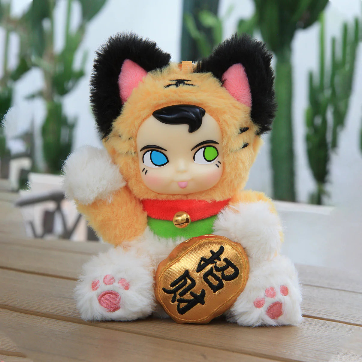 SAMSAM FORTUNE CAT PLUSH Blind Box: A tiger-patterned plush with a vinyl face, mismatched eyes, and a gold coin, seated among potted cacti.