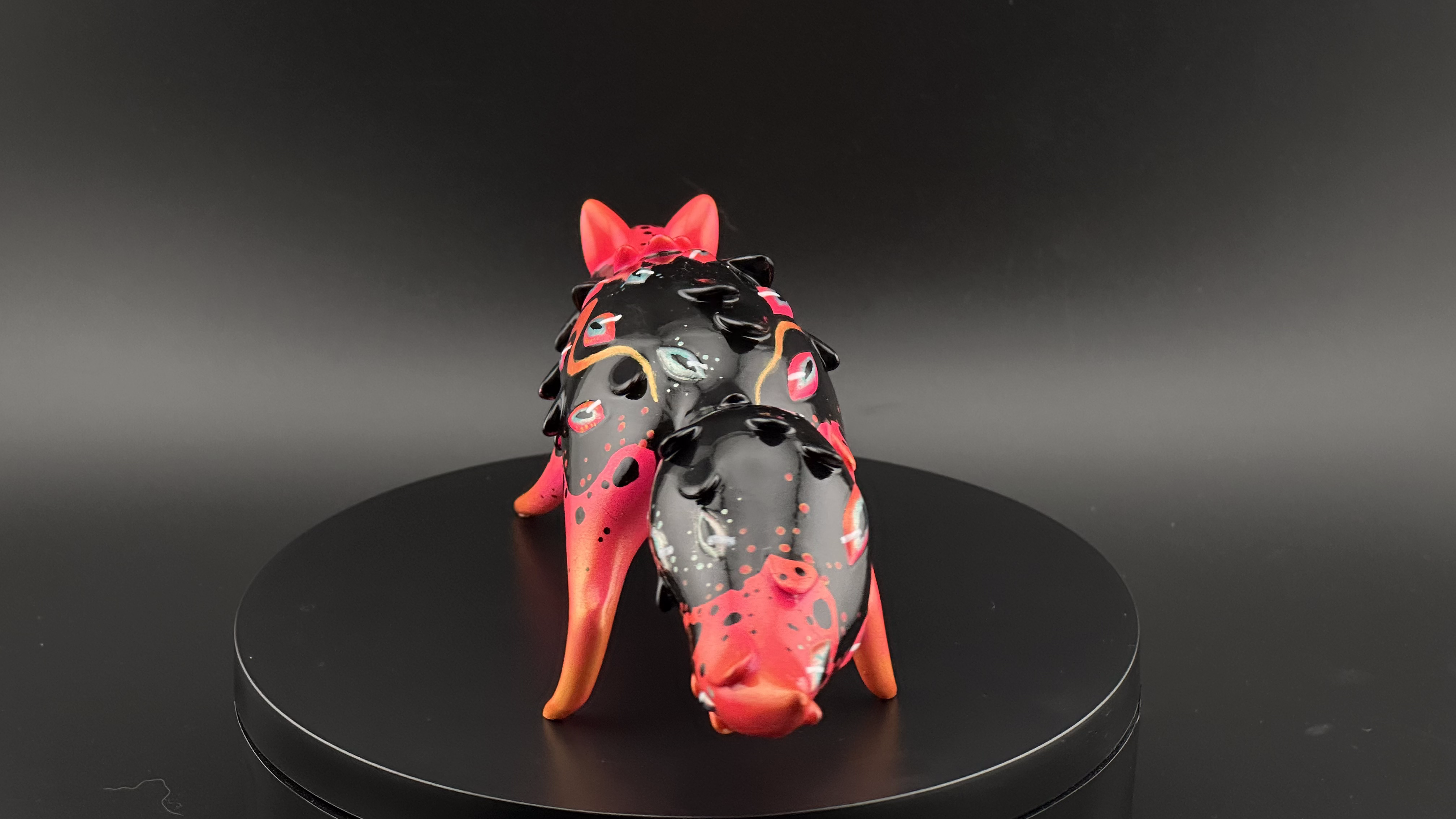 Whispers Screaming sculpture: stylized boar-like figure with vibrant red-orange legs, black body, eye motifs, and spikes, crafted by Absolute Creature Vibes x Faunwood.
