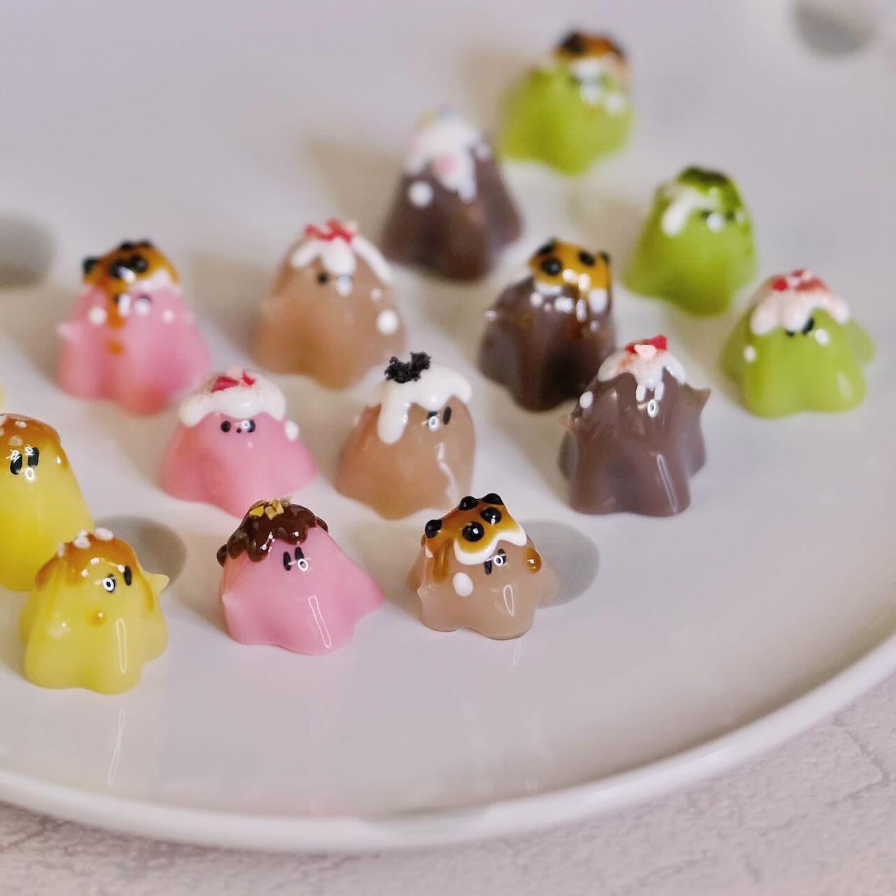Mini dessert ghost toys in various flavors, including pudding and strawberry, displayed on a plate, each measuring 1.5-2 cm in height.