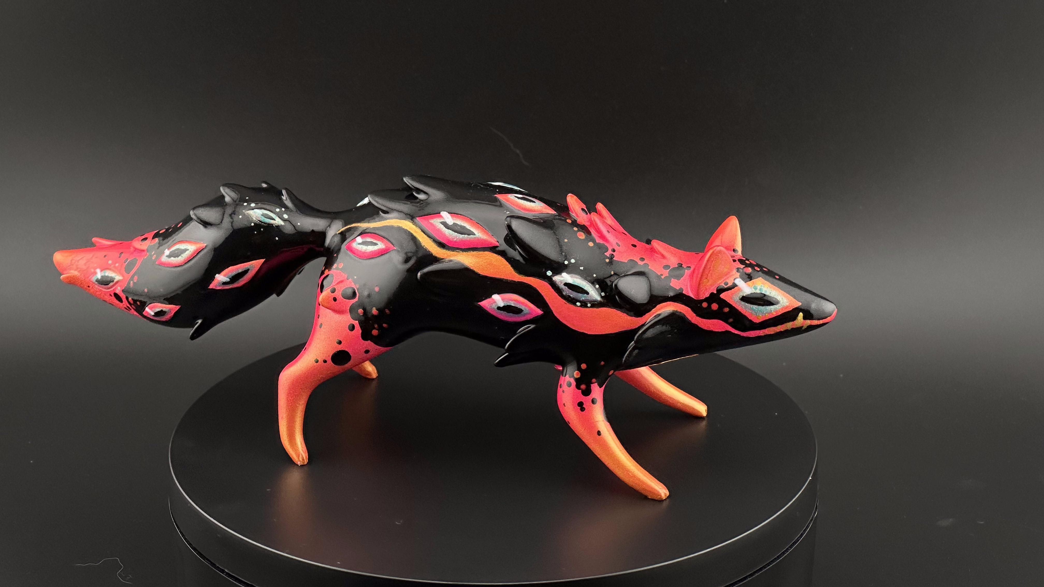 Stylized fox sculpture with flowing lines, glossy black finish, vibrant orange-red accents, eye motifs; part of ORACLE Group Show by Absolute Creature Vibes x Faunwood.