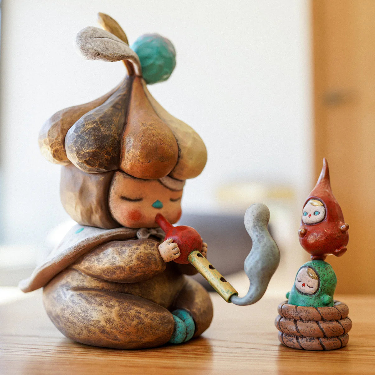 The Beanie Charmer - X-Mas Edition by Pucky, features whimsical ceramic figures: a pipe-playing child and two gnome-like companions, embodying dreamlike artistry.