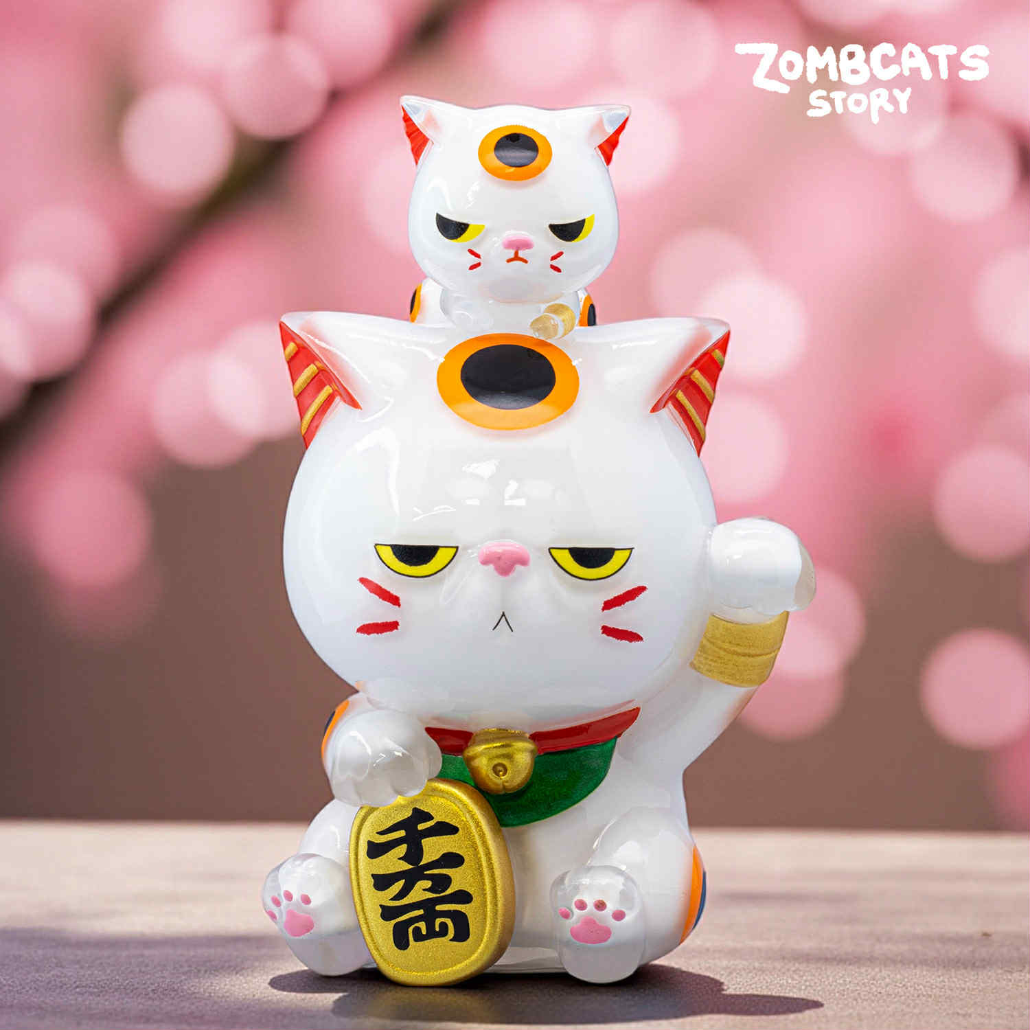 Zombcats Story - Grumpy Maneki LOTTERY: A glossy white ceramic figurine featuring two-tiered cats with raised paws, gold coin, and orange-red markings on ears and cheeks.