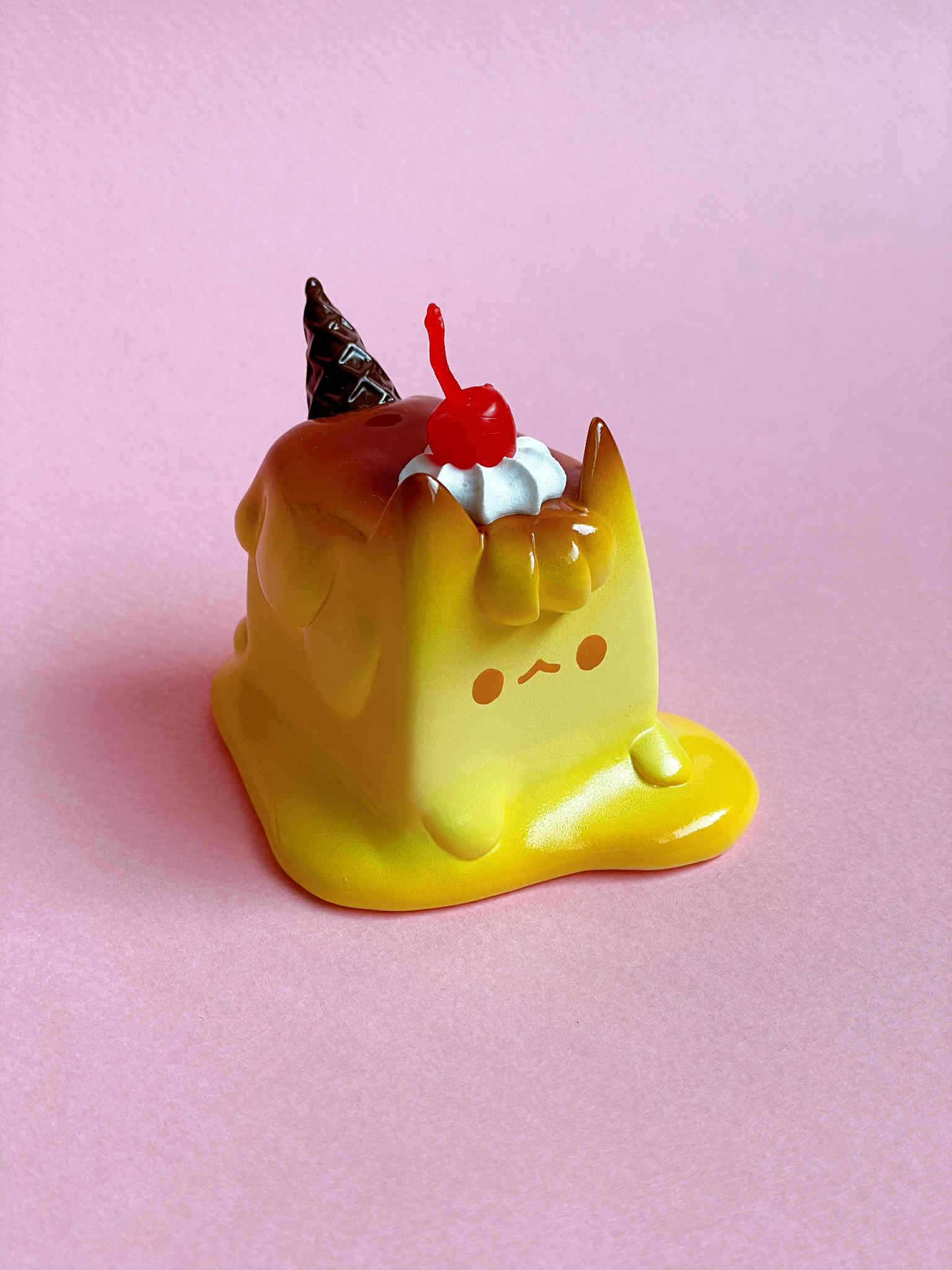 Pudding Cat by Rato Kim: A whimsical vinyl figurine of a melting custard-like cat topped with whipped cream, cherry, and chocolate accents.