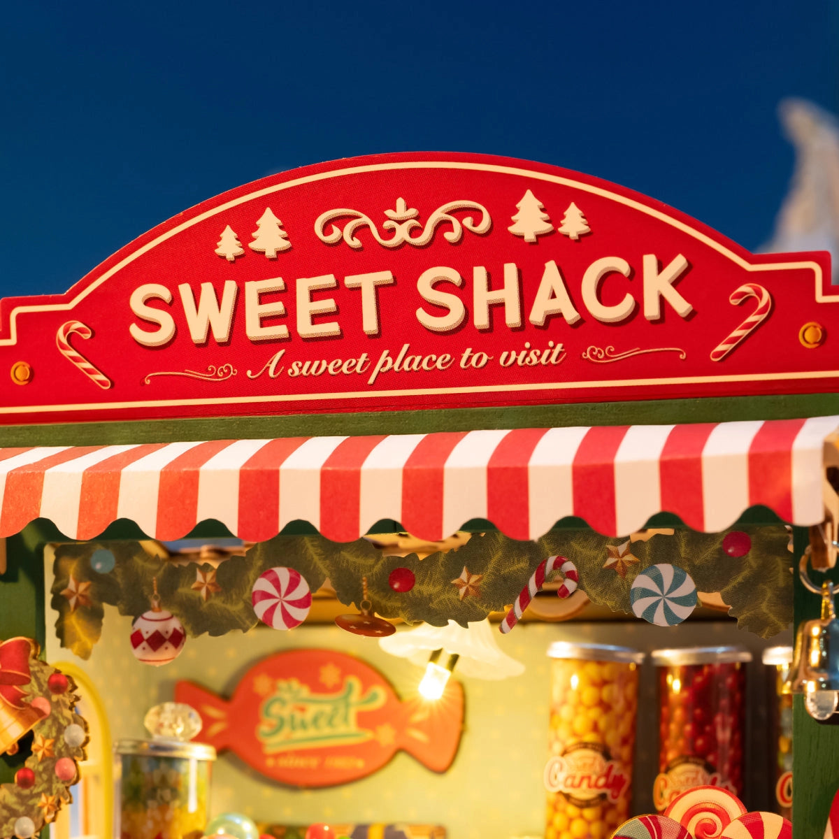 Rolife DIY Miniature House - Christmas Candy Stand DS043: A festive candy kiosk model with jars of sweets, peppermint ornaments, and candy canes under a striped awning.