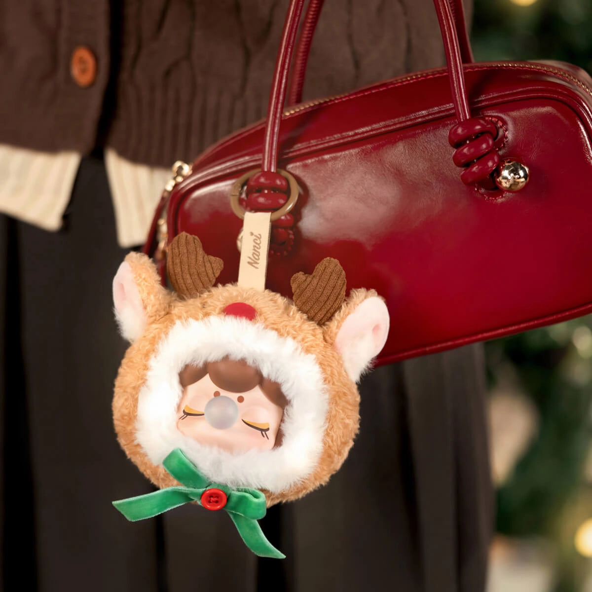 Rolife Nanci's Christmas Gift Plush Pendant PZC13 adorns a red handbag, featuring a reindeer-themed doll charm, perfect for holiday decoration or gifting.