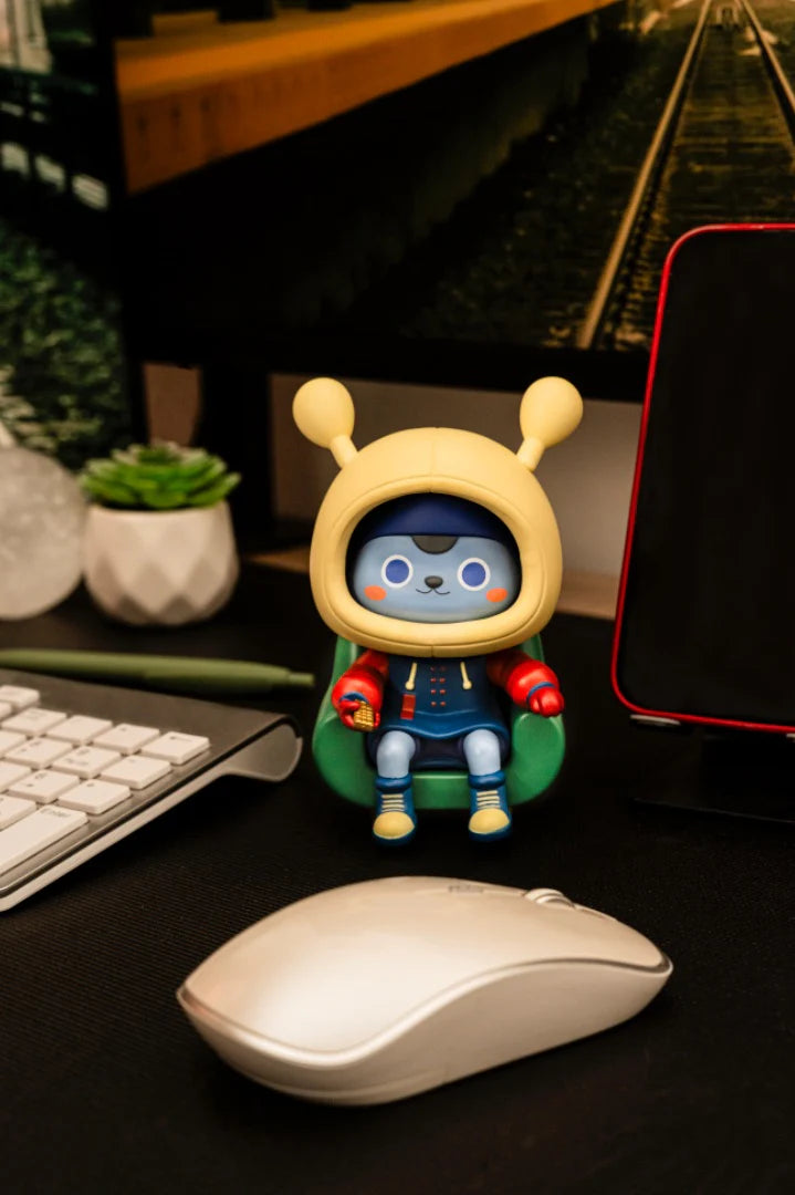 Napa Series One vinyl toy in green chair, with stylus, mouse, keyboard, succulent, decorative sphere, and smartphone; part of Strangecat Toys' exclusive collectible series.