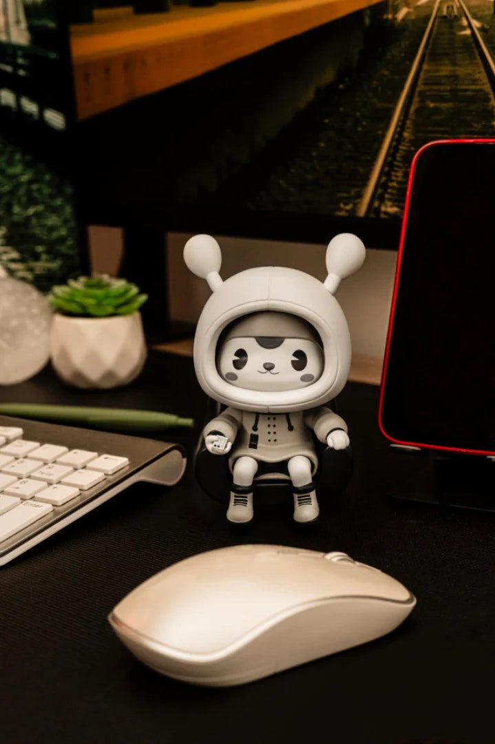 Napa - Retro figurine sits on a mini chair with a remote, surrounded by a mouse, keyboard, succulent, and smartphone on a desktop workspace.