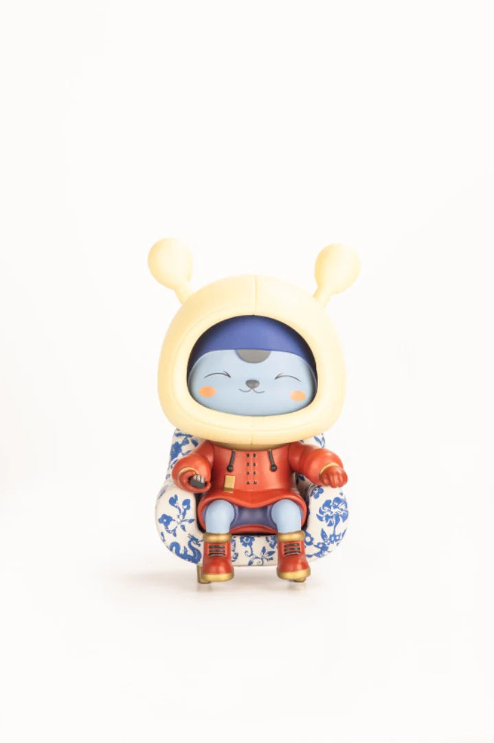 Napa - Porcelain: A 5 vinyl cat-like figure in a red outfit, seated in a blue-patterned armchair, inspired by traditional ceramics. Limited edition collectible.