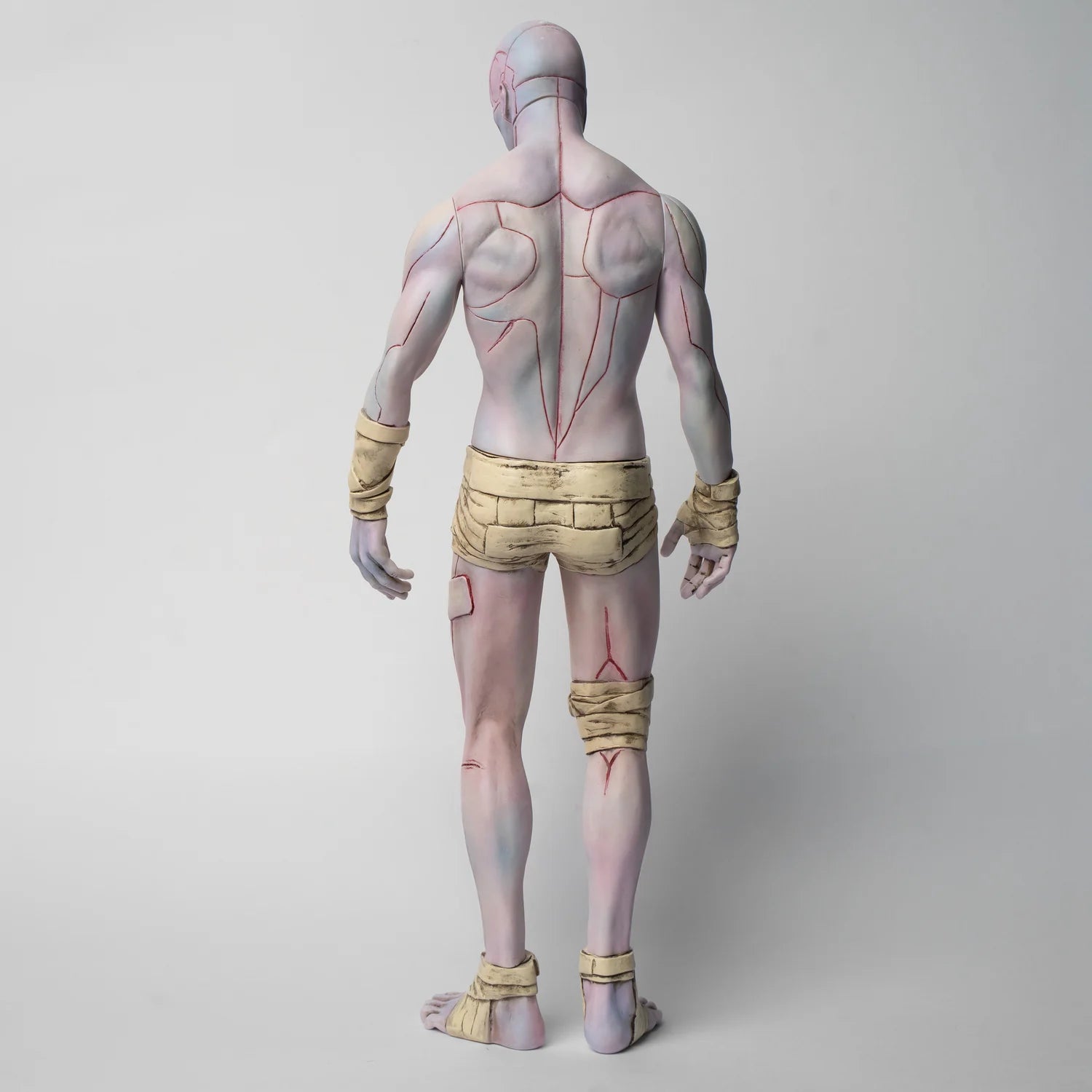 Frankenstein: The Creature V1, a 30cm soft vinyl figure, displays a minimalist anatomical design with red lines over pale skin and cloth wrappings.