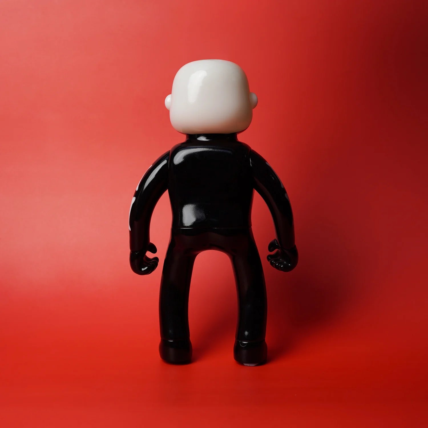 MR NOBODIES - SKELETON (GID GREEN) - Preorder: Glossy vinyl figurine with a featureless white head, black body, rear view, against a red background.