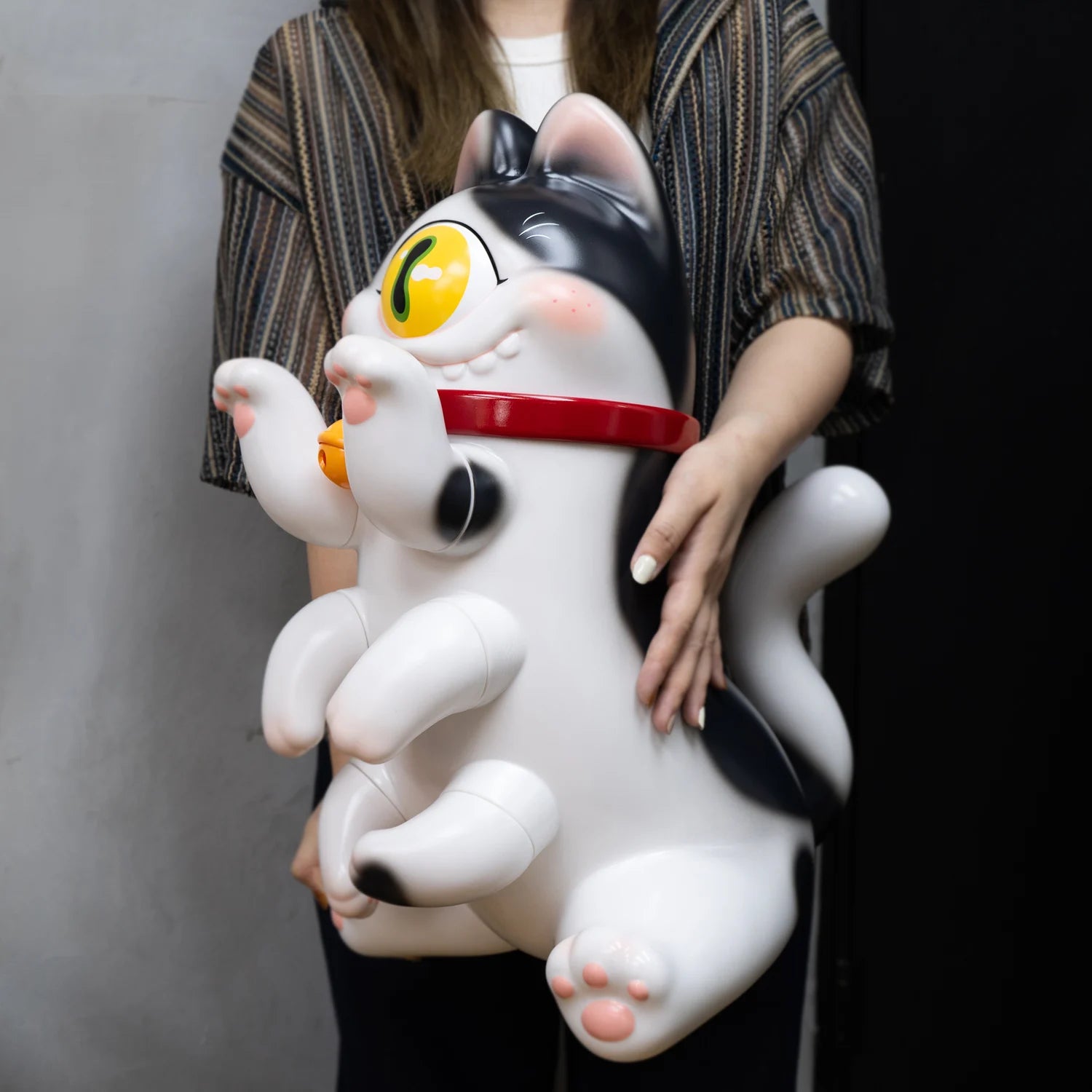 GIANT SIZE KITTI XL: A 50cm soft vinyl cat figure with an articulated eye, designed by Abao, held by a woman.