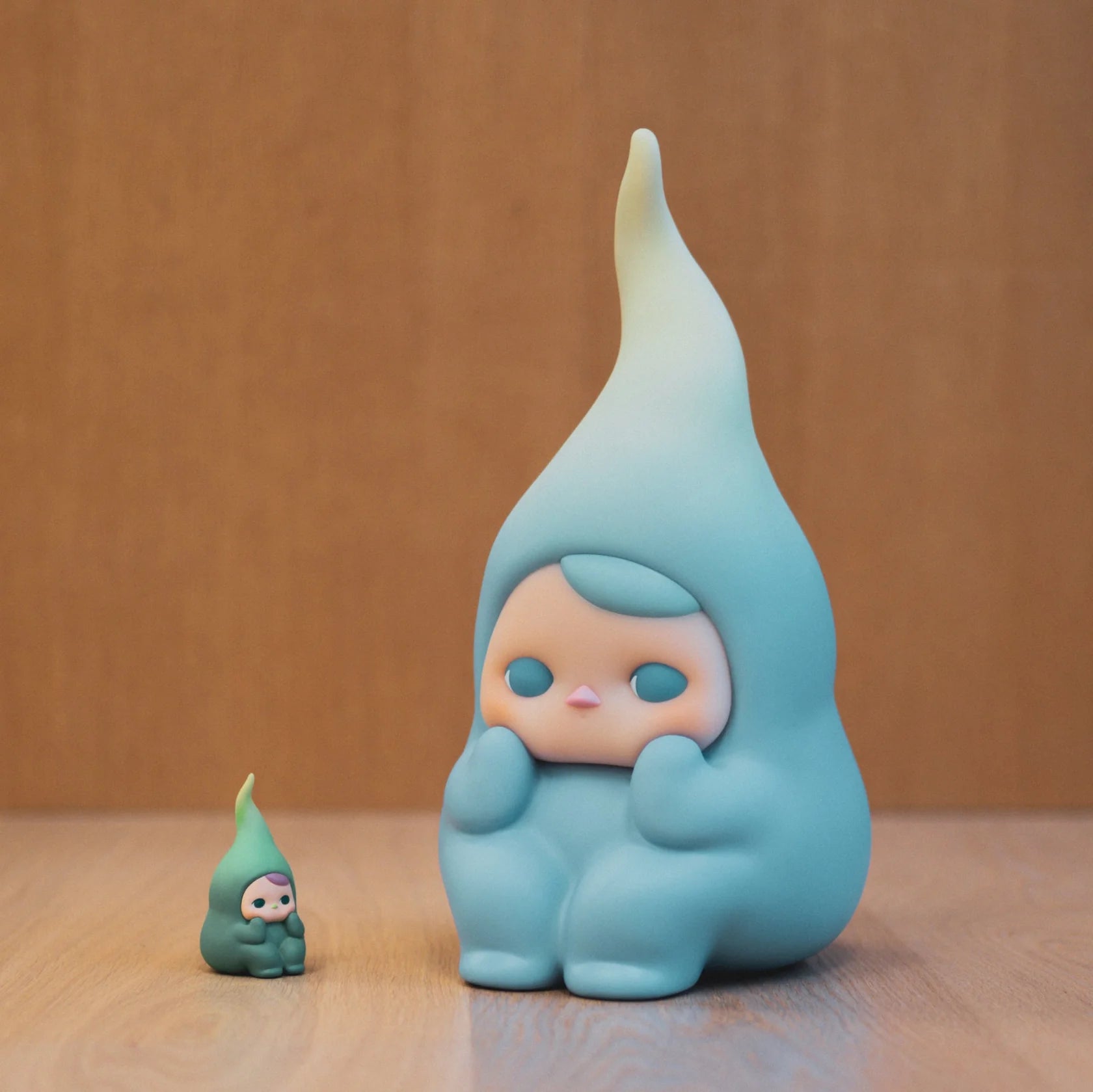Big Beanie by Pucky: Two pastel-blue droplet-shaped figures, one large (24cm), one small, featuring rounded bodies and tapered hoods, sit on a wooden surface.