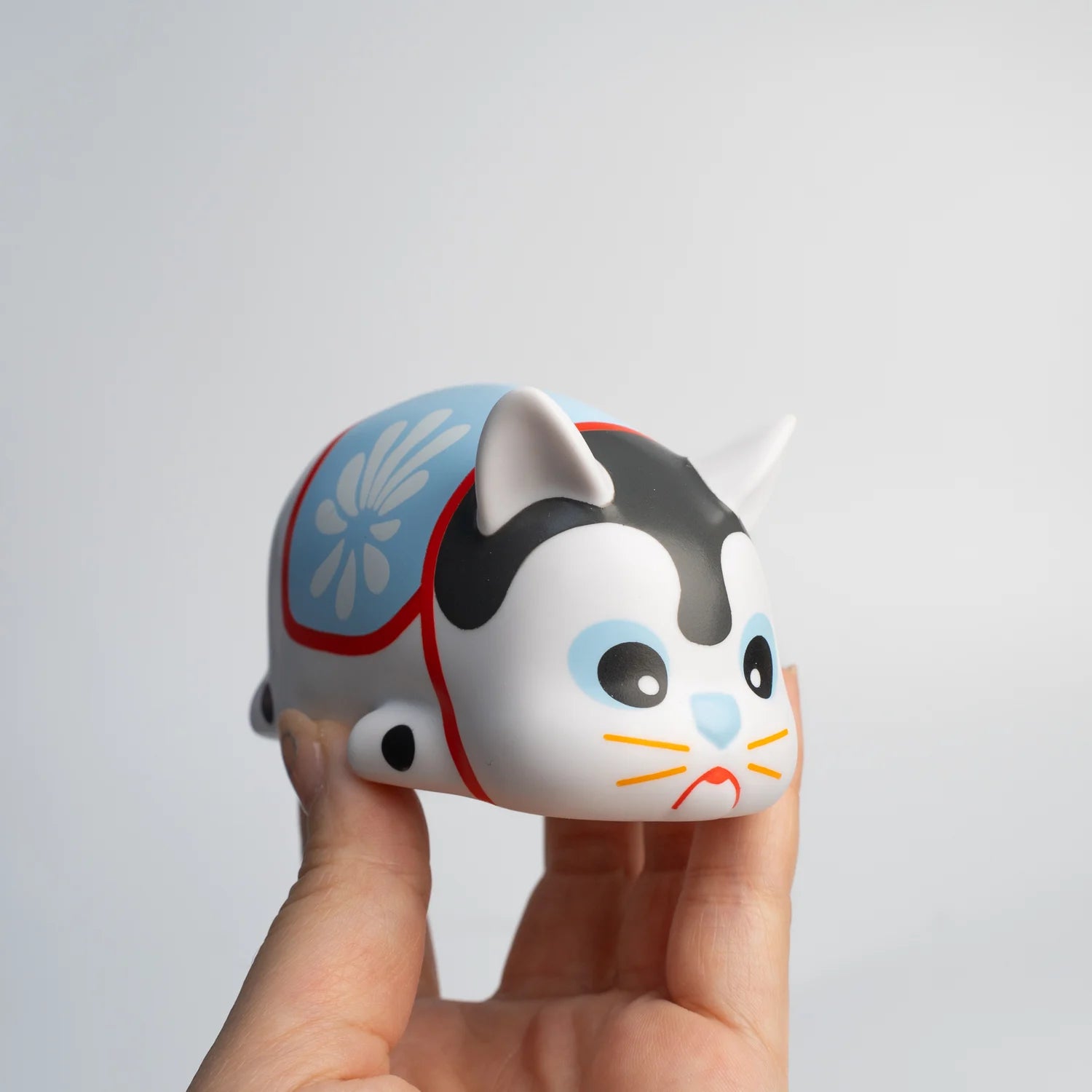 Alt text: A hand holding a toy cat, NIMBUS HARIKO TTE EDITION - Preorder, a soft vinyl animal figure designed by Paulus Hyu.