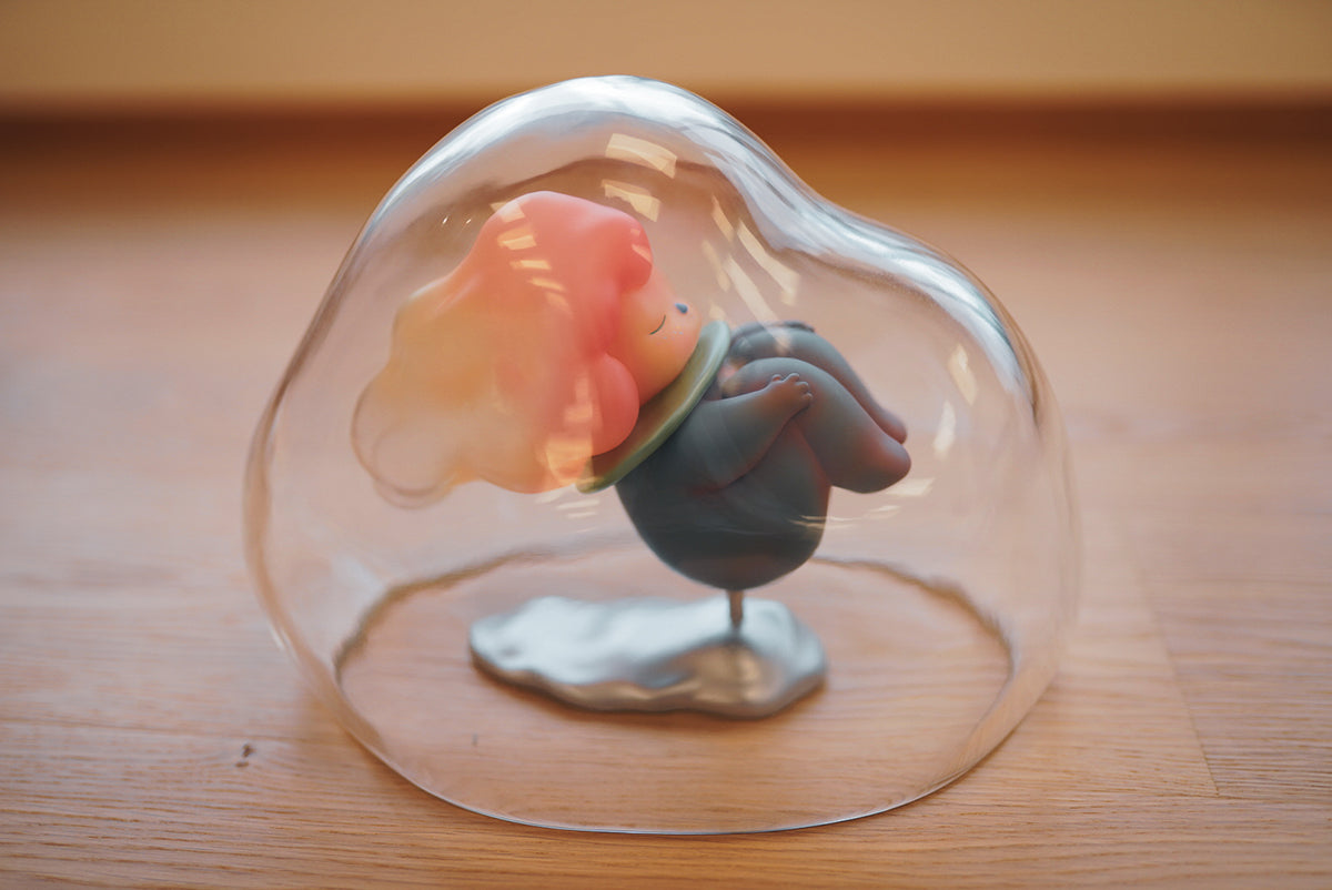 Jelly Girl by Pucky vinyl figurine in glass dome, with cartoon animal toy and pink toy in bowl, close-up of toy.