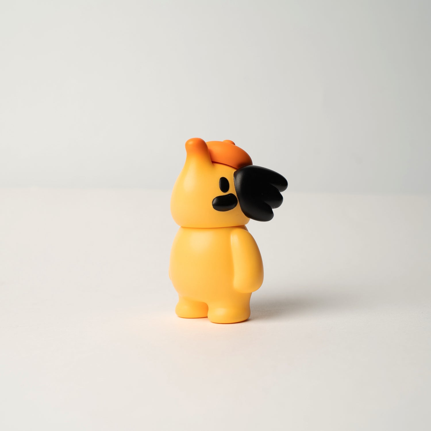 ELFIE HERE I AM! 100% OHIGEnoPON EDITION vinyl toy in yellow with orange cap, featuring unique black detail on face, standing on a neutral surface.