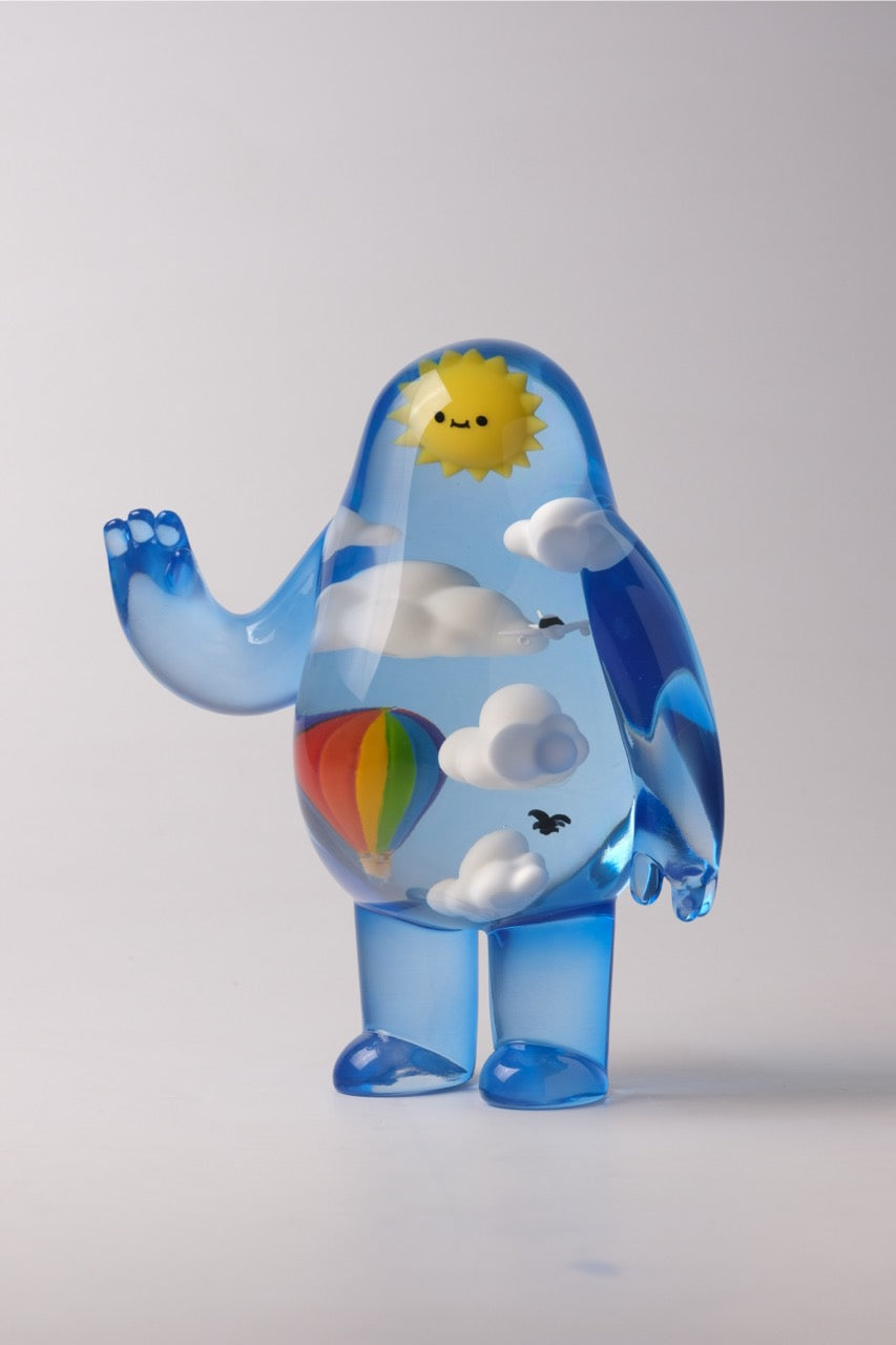 Sky Guy by Sad Salesman, a translucent blue figurine, features a mini sky scene with clouds, sun, hot-air balloon, and bird inside.