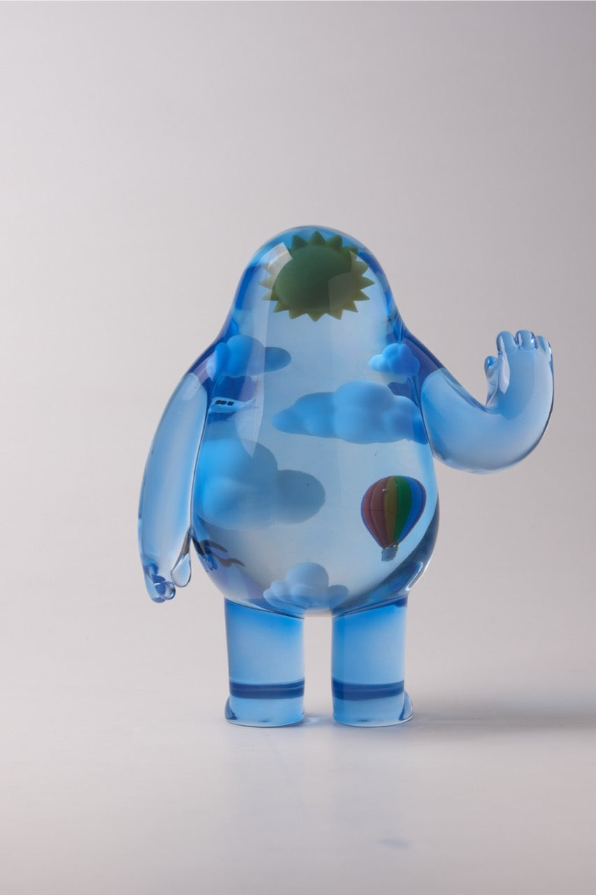 Sky Guy by Sad Salesman: A translucent blue art figure featuring clouds, a hot-air balloon, and a sun, resembling a whimsical humanoid with a miniature sky scene inside.