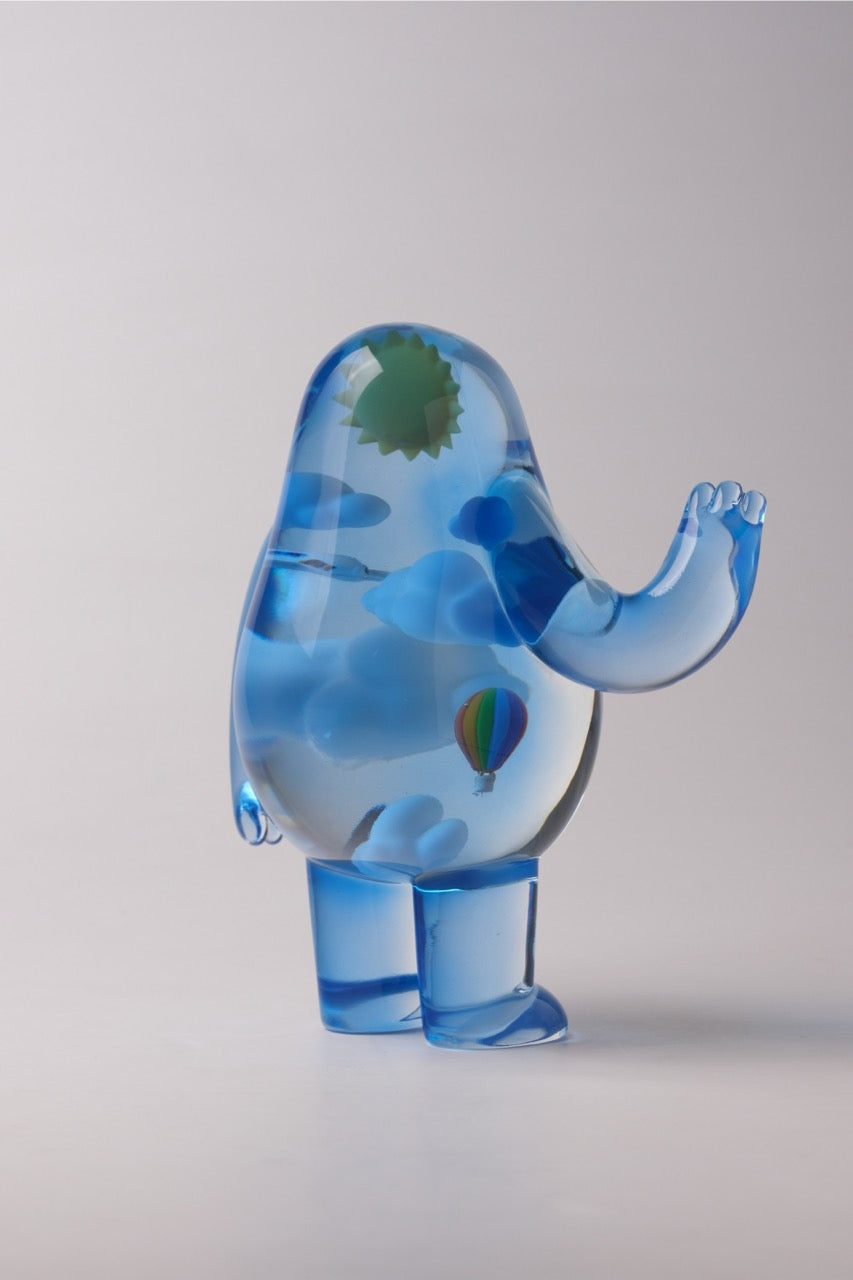 Sky Guy by Sad Salesman: A whimsical, translucent blue figurine with clouds, a green sun, and a rainbow balloon inside its playful, blob-like form.